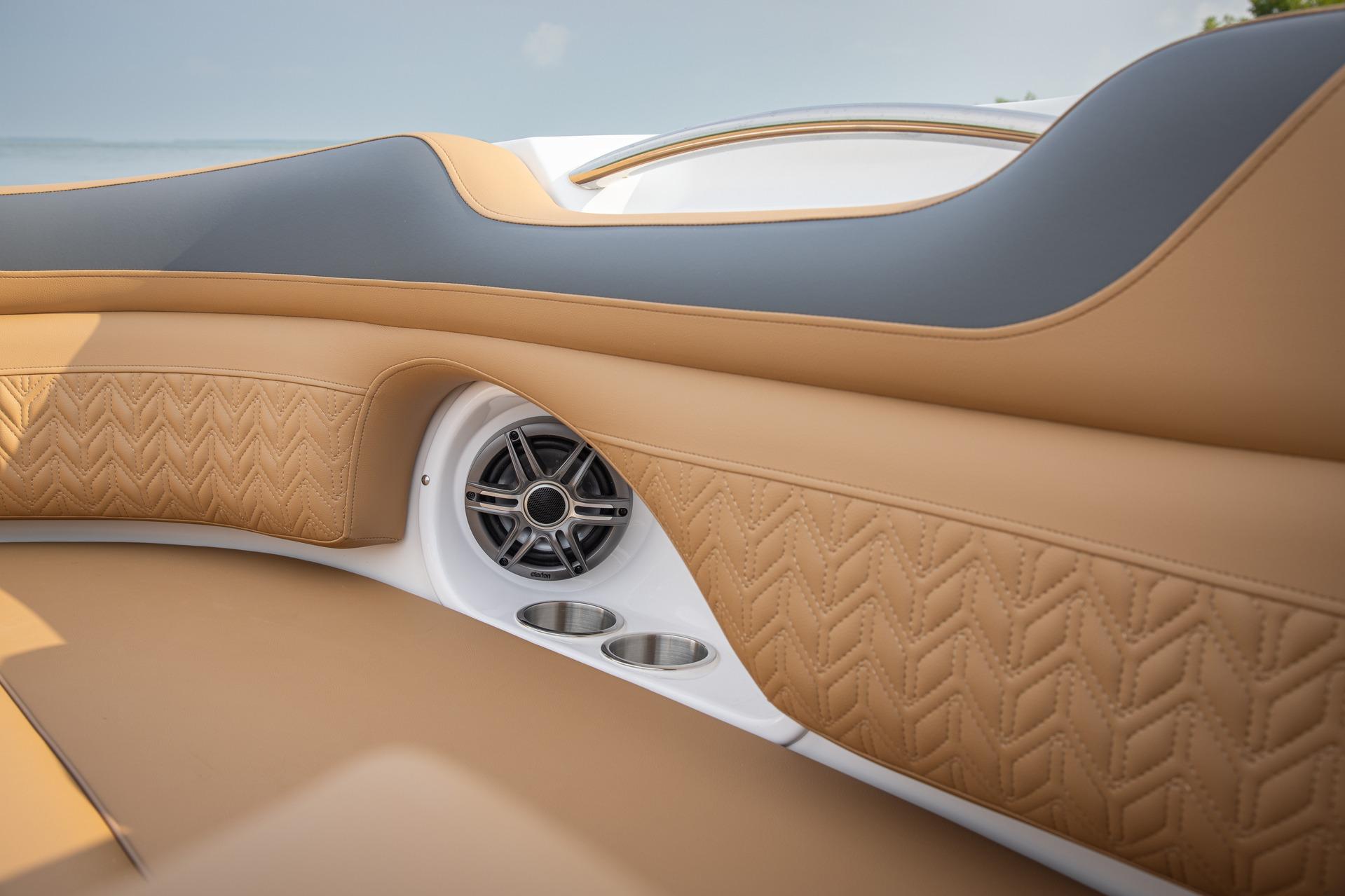 Luxurious interior of 2026 Hurricane SunDeck 2690 OB boat with tan upholstery and speaker.