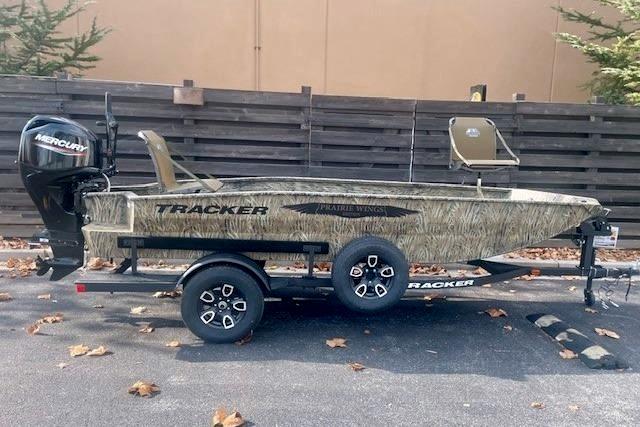 2026 Tracker Grizzly 1650 T Prairie Wings Edition boat on trailer, camo design, parked outdoors.