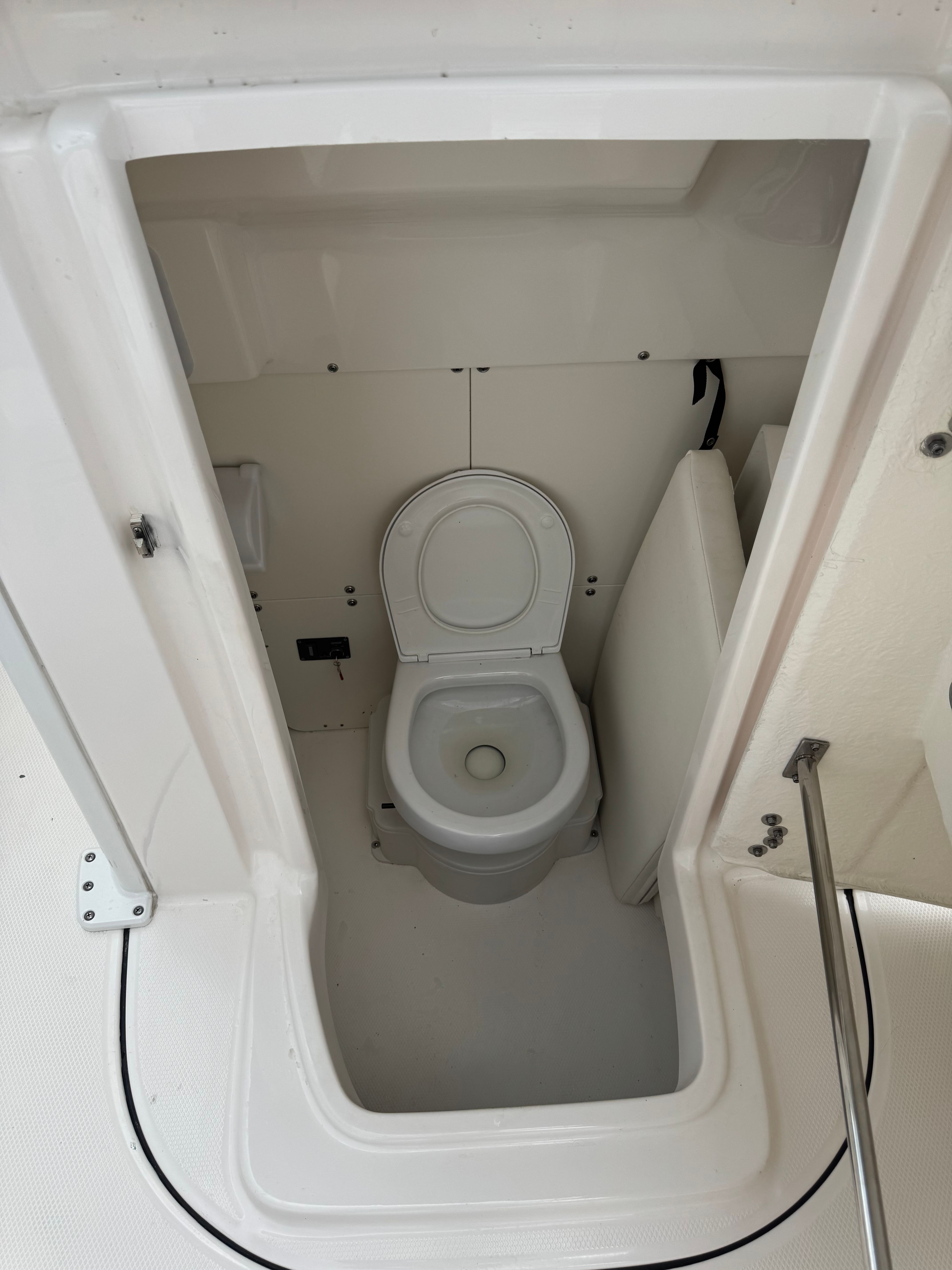 Interior view of a boat toilet with white seat and walls.