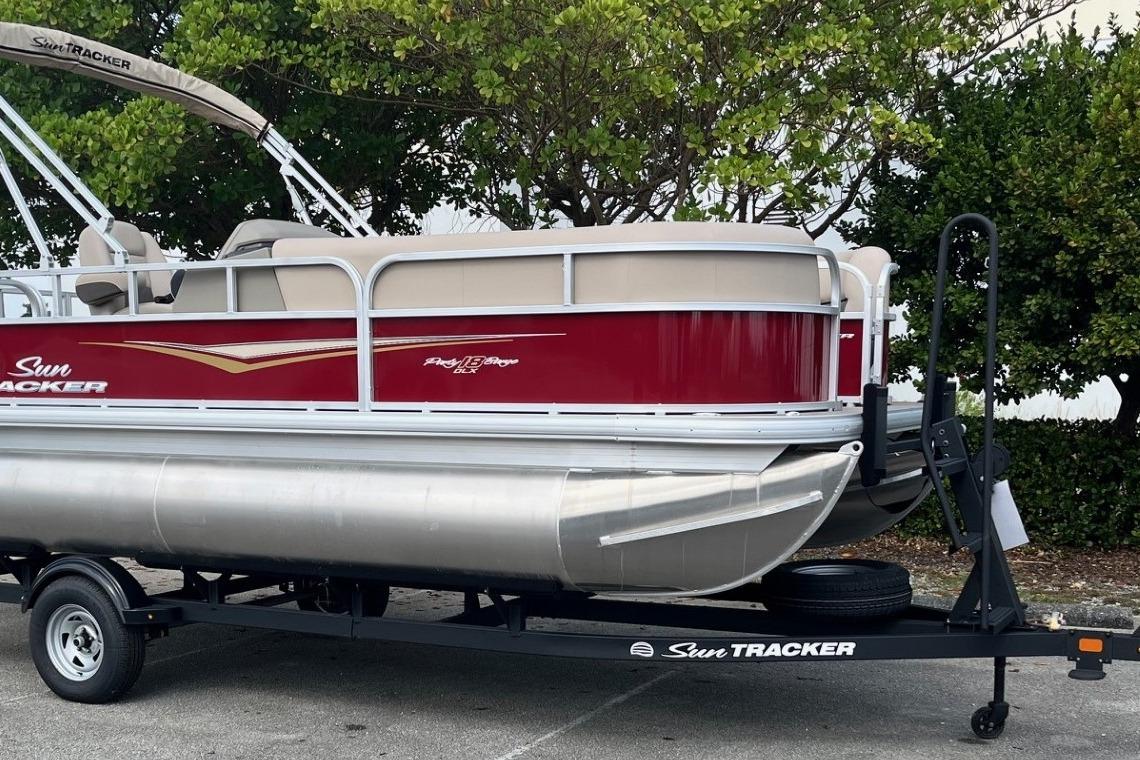 2025 Sun Tracker Party Barge 18 DLX pontoon boat on trailer, parked outdoors.