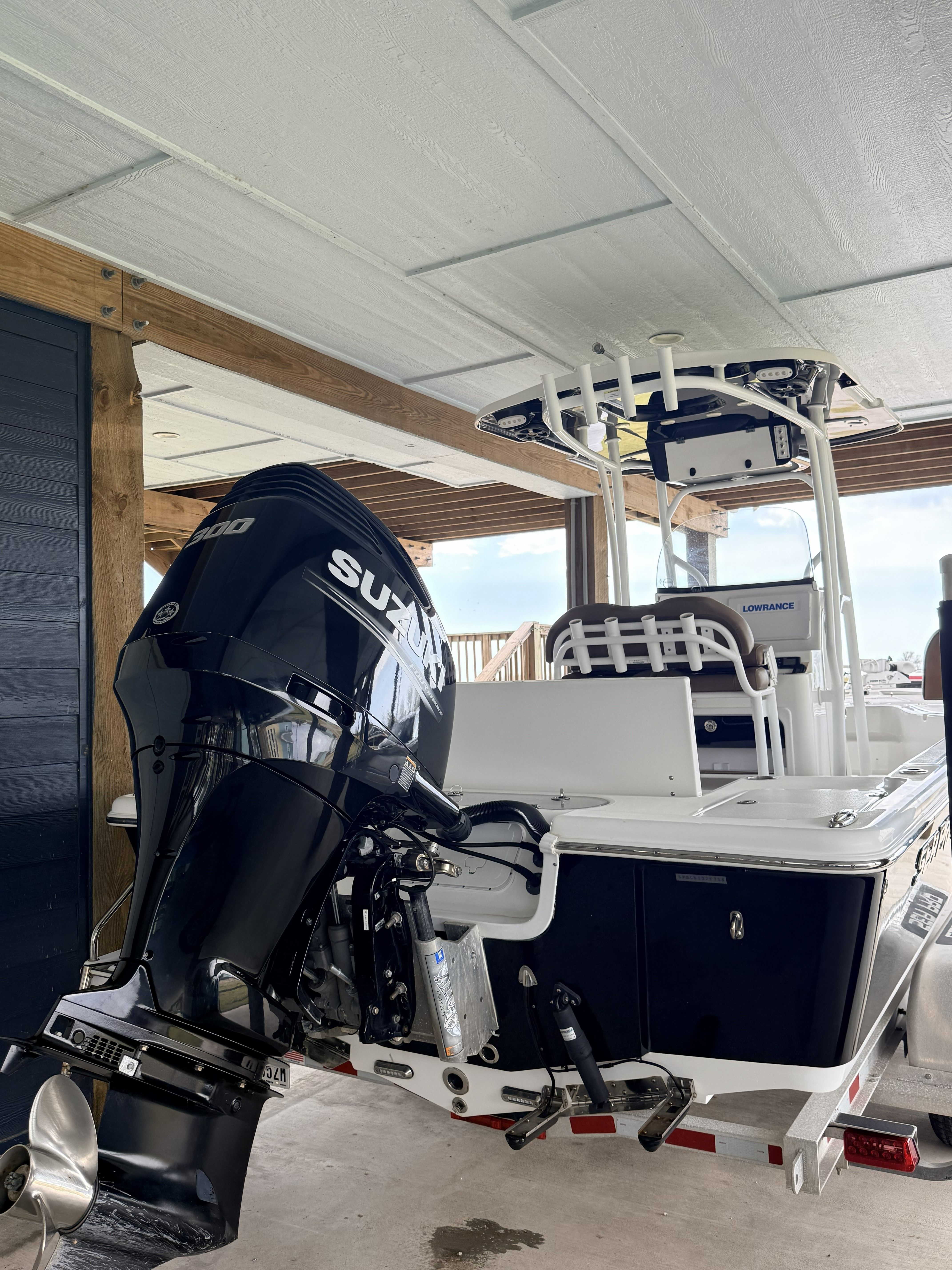 A 2018 Sea Pro 248 Bay boat with a Suzuki outboard motor, parked under a covered area.