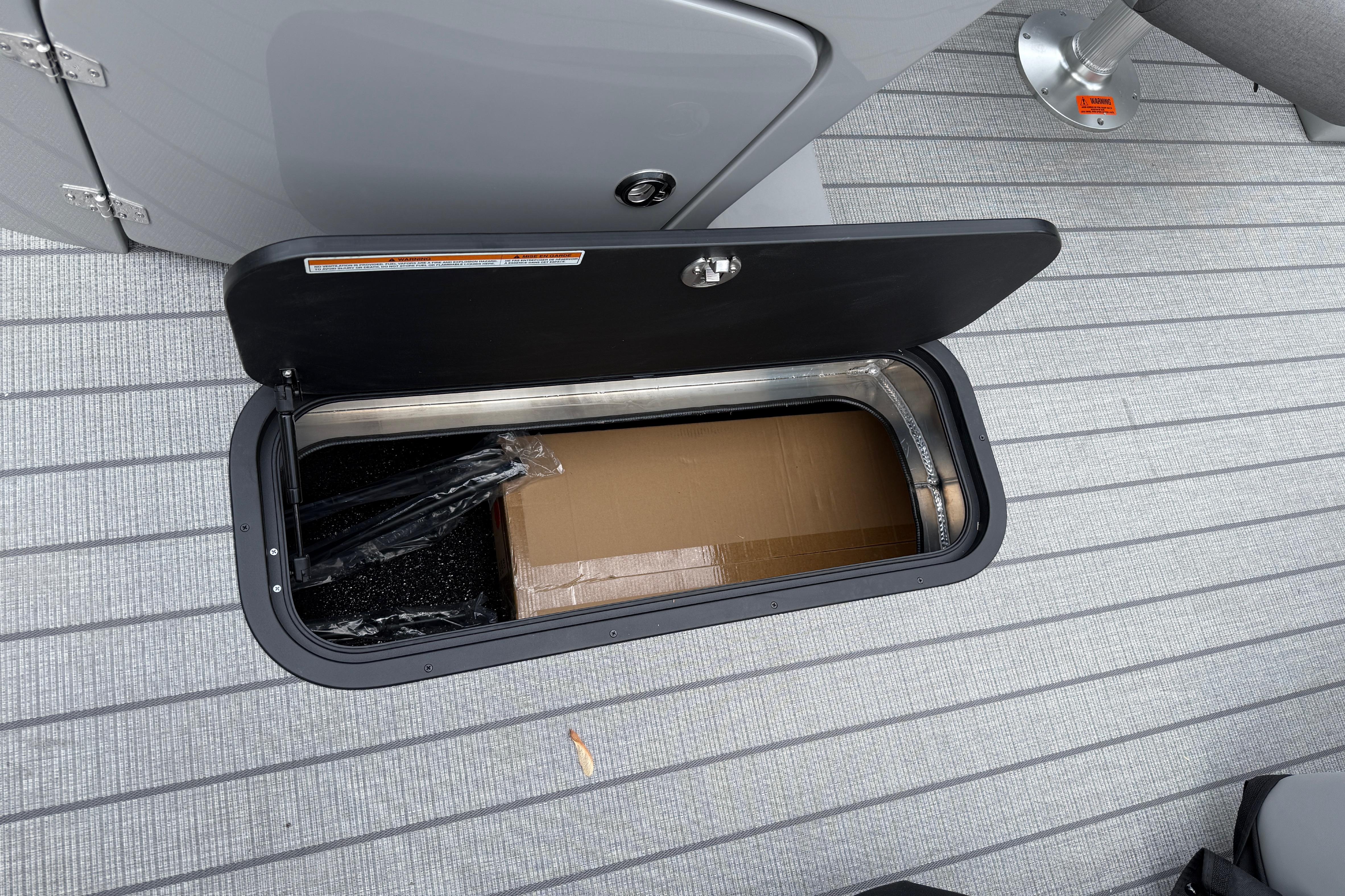Storage compartment on 2027 Manitou Aurora RF 23 boat, open with visible contents.