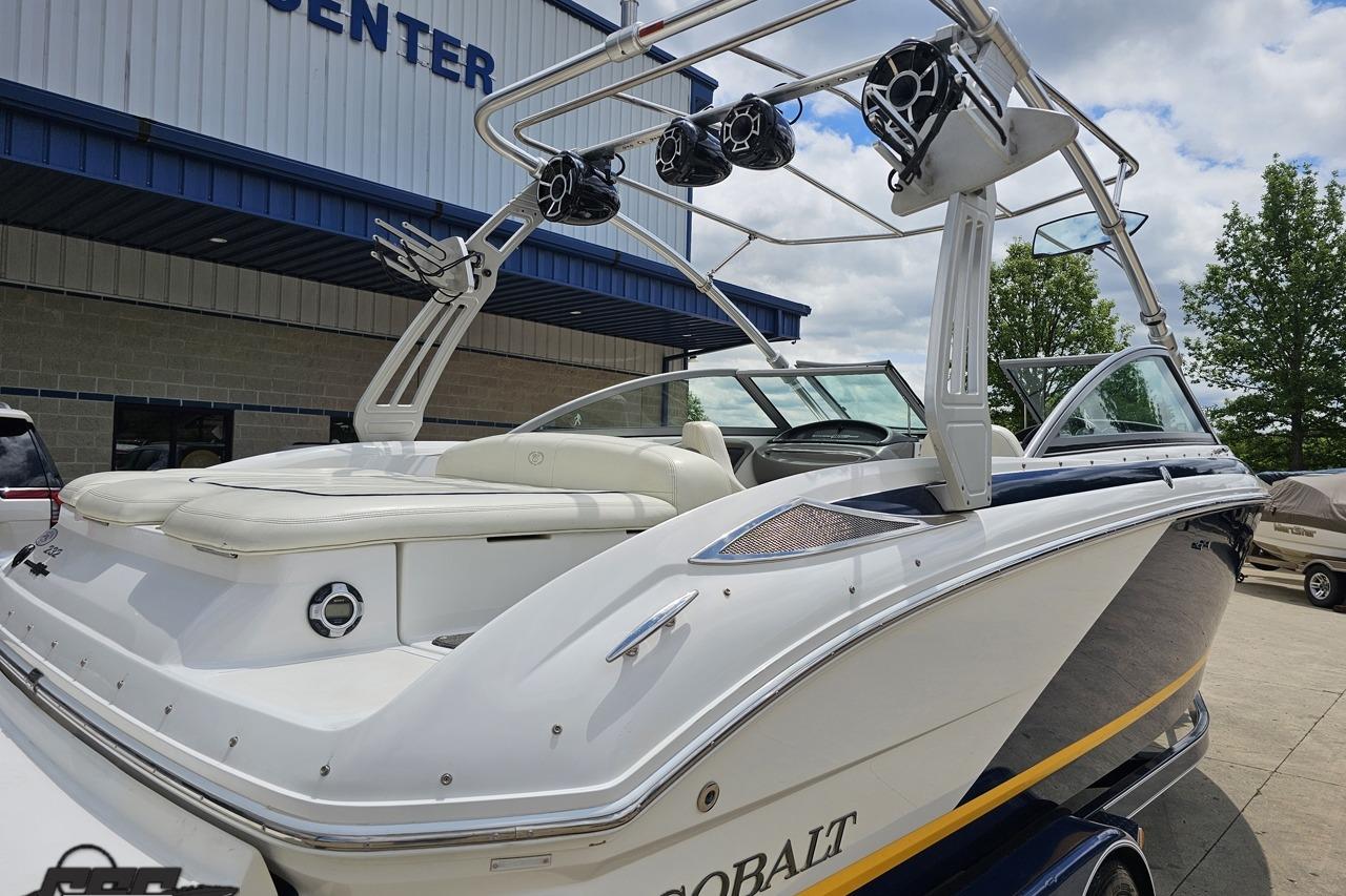 2010 Cobalt 232 WSS boat with tower speakers, parked outside a marine center.