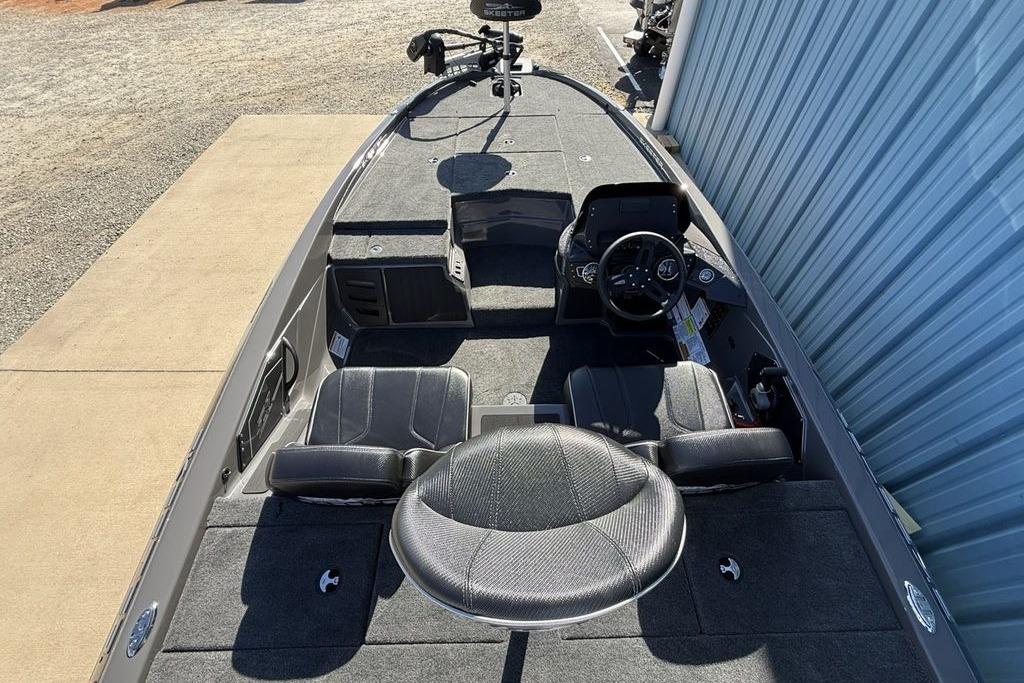2026 Skeeter ZX150 boat interior with steering console and seating, parked near a blue wall.