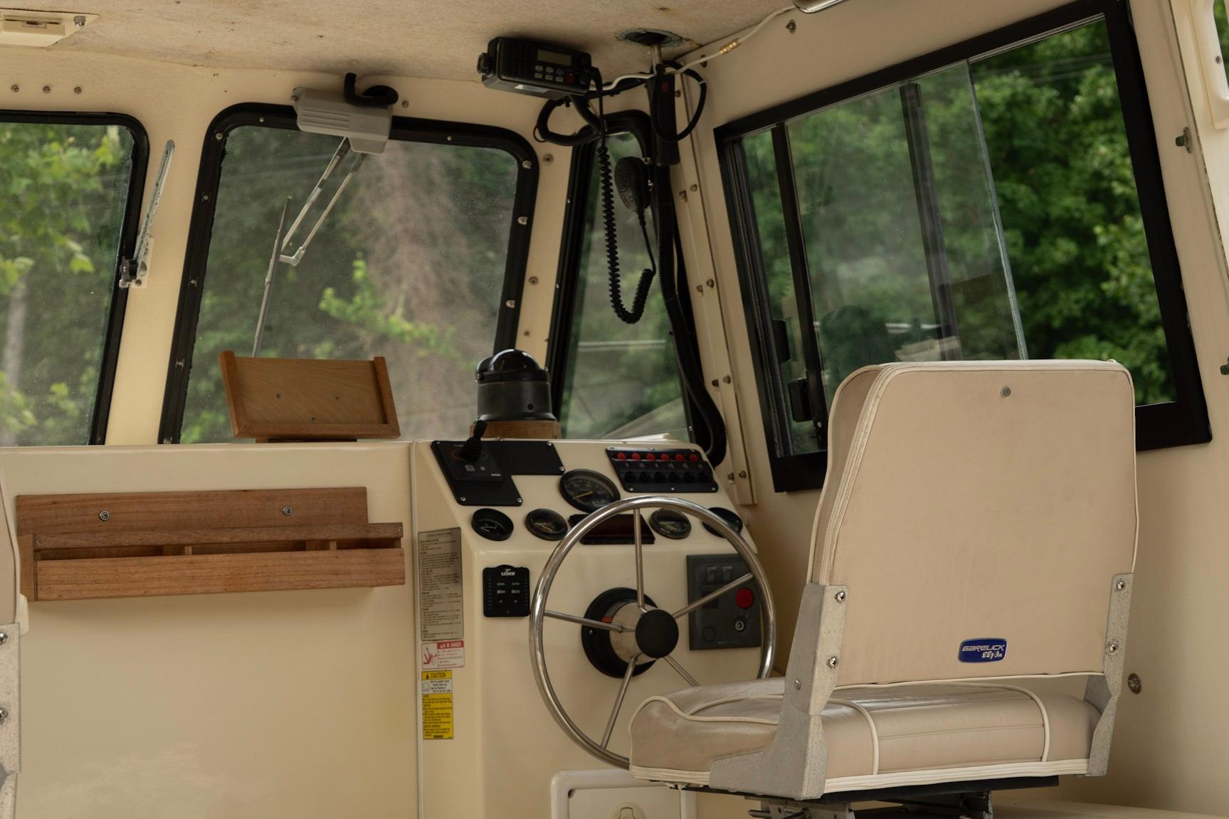 Interior helm of 2006 Atlas Boat Works Acadia 25, featuring steering wheel and controls.