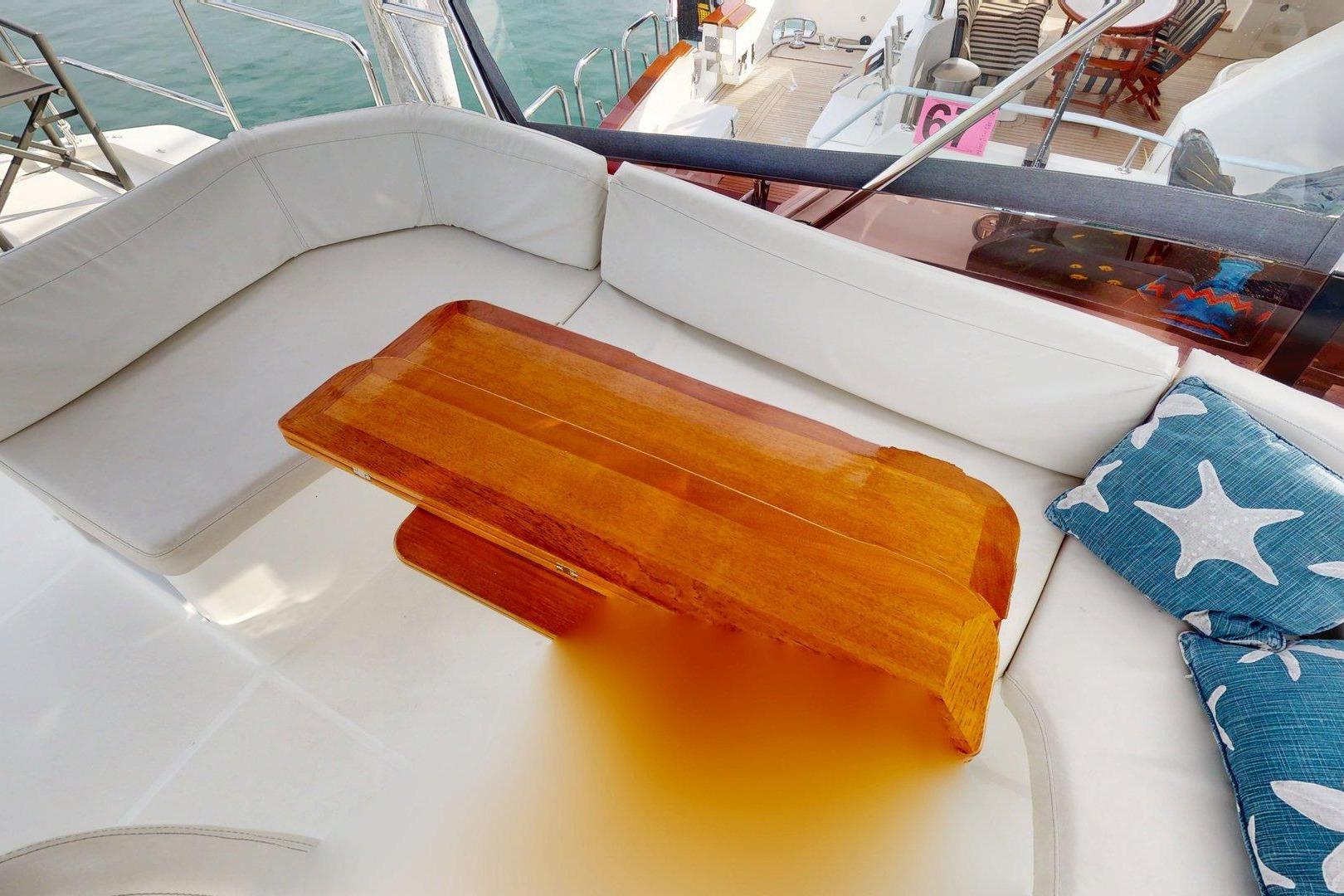 Cozy seating area on 2021 Beneteau Swift Trawler 35 with wooden table and starfish cushions.
