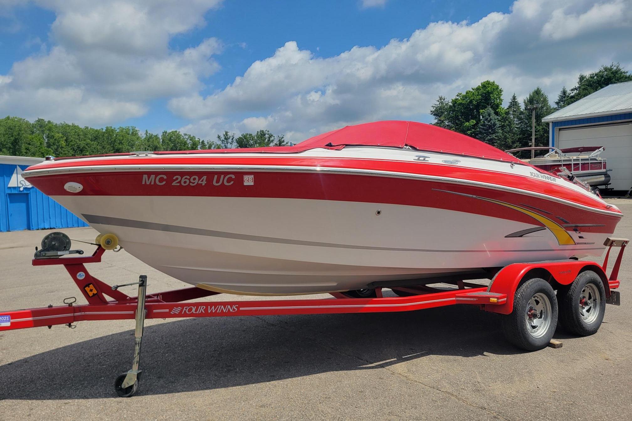 2007 Four Winns 200 Horizon boat on trailer, red and white design, parked outdoors.