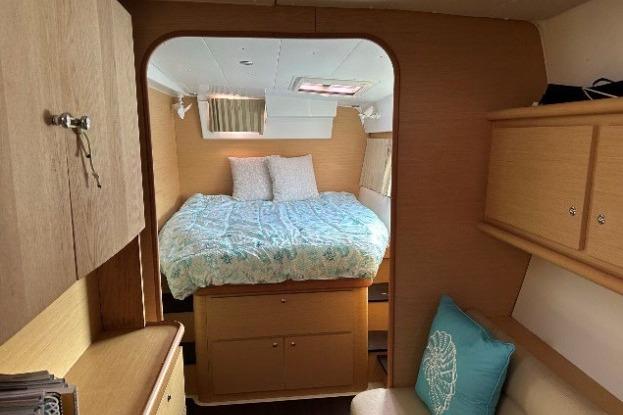 Cozy cabin interior of 2010 Lagoon 421 catamaran with bed and wooden furnishings.