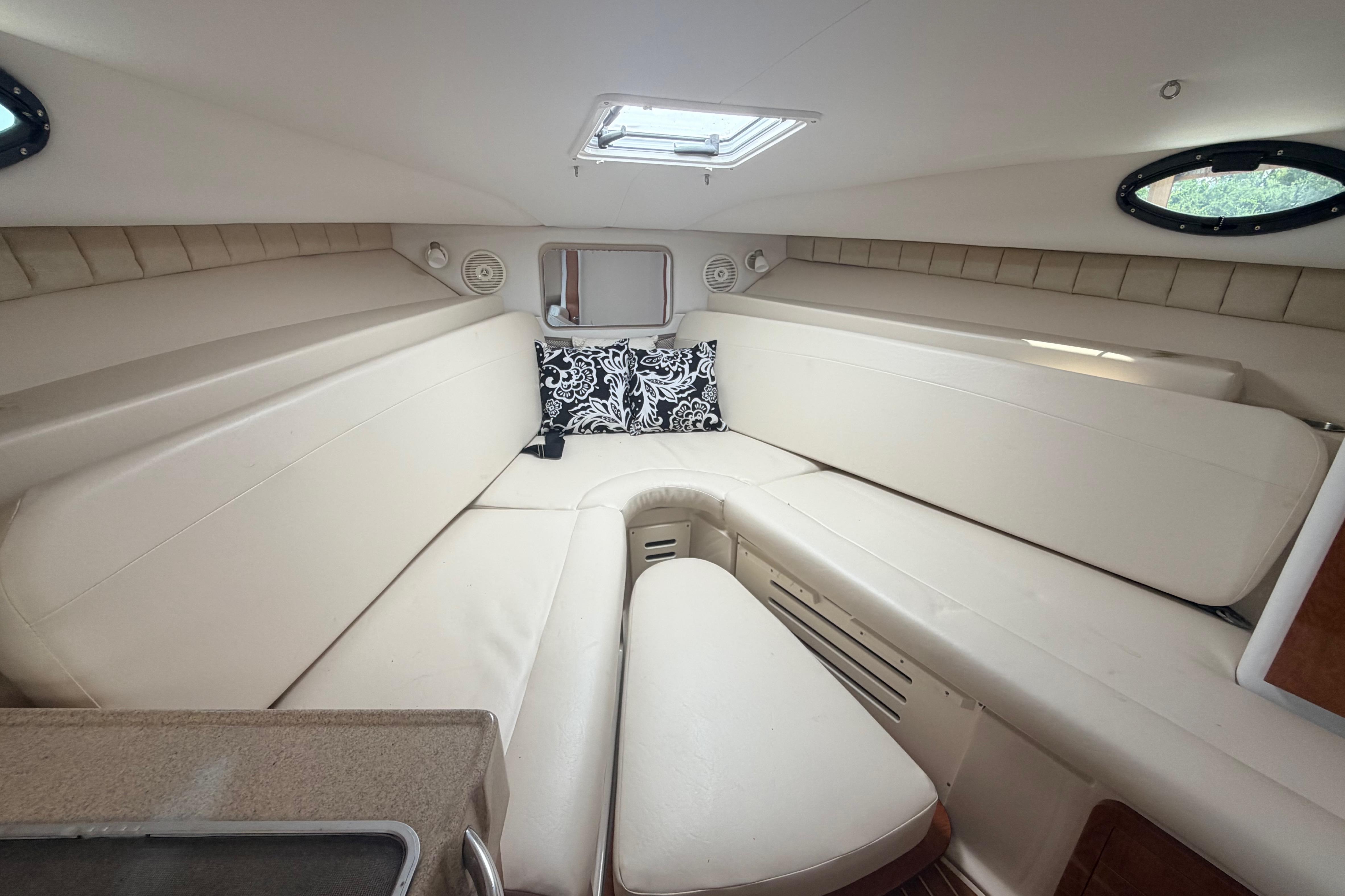 Interior cabin of 2015 Wellcraft 290 Coastal boat with beige seating and decorative pillow.