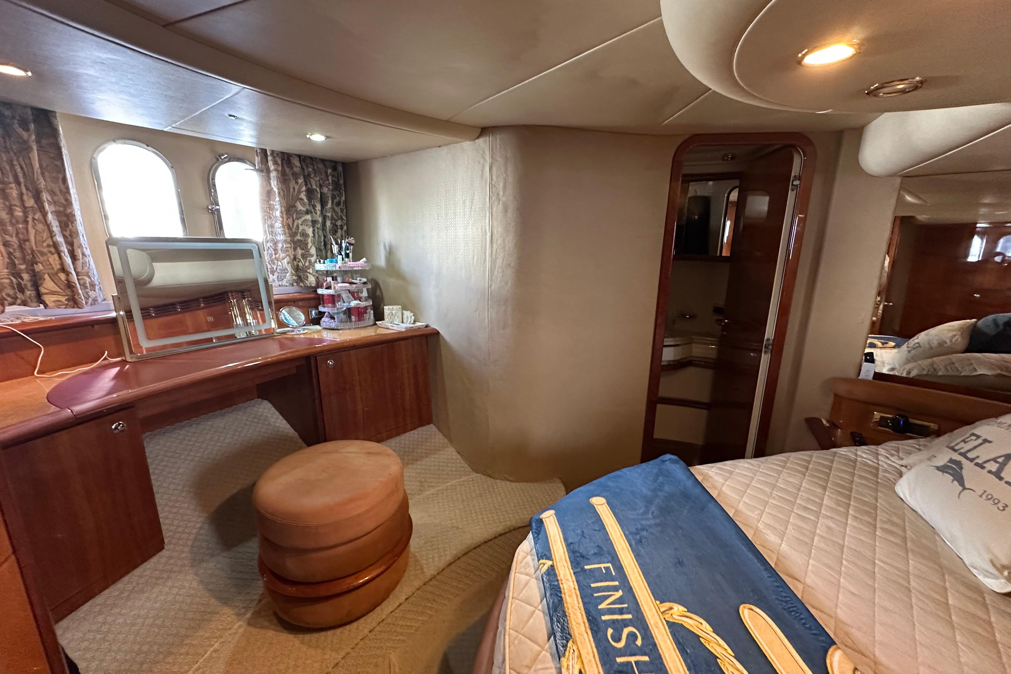 Luxurious interior of a 2004 Azimut 55E yacht featuring a vanity and cozy bedroom.