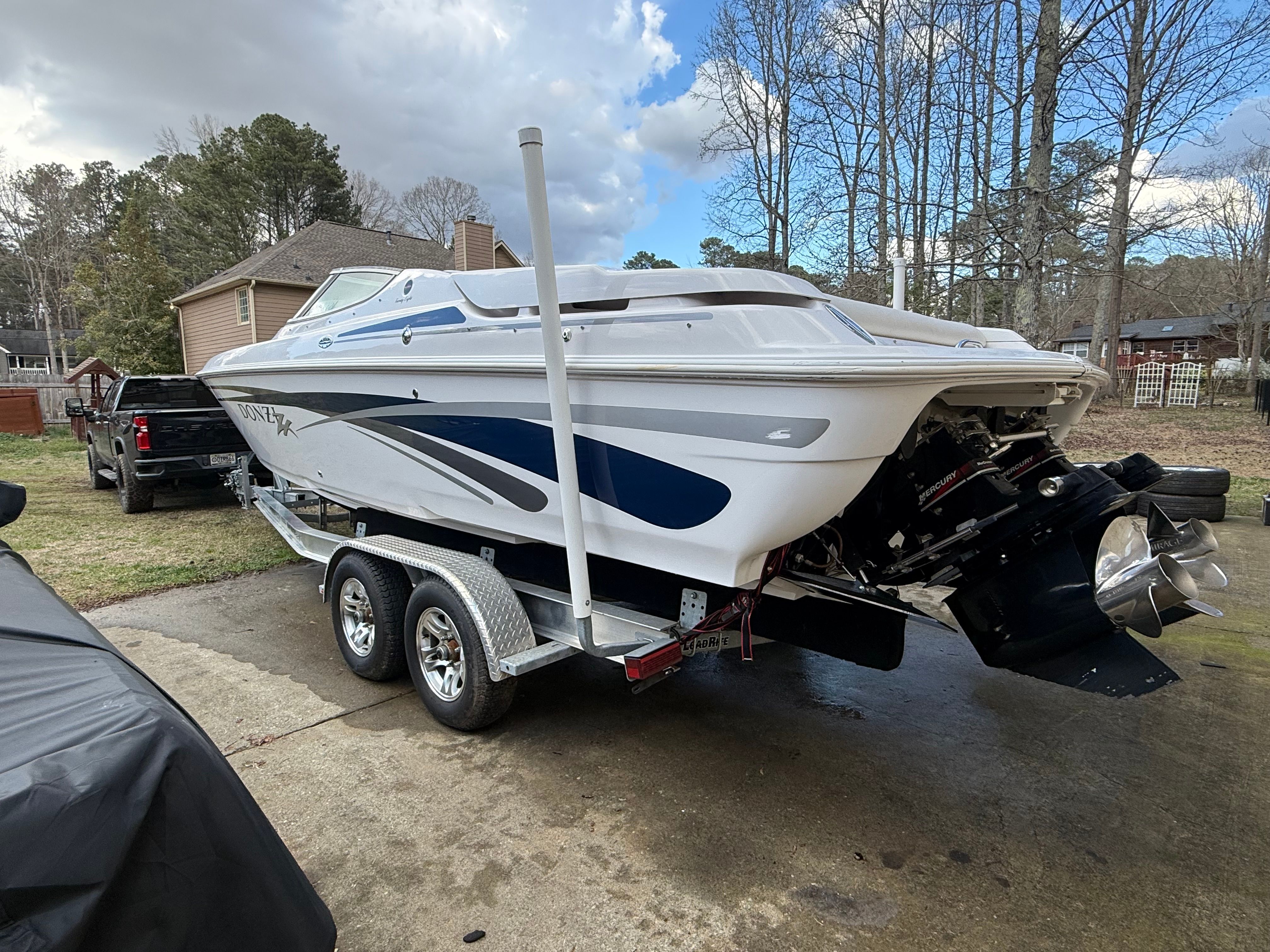 A white 2003 Donzi 28 ZX boat on a trailer in a yard.