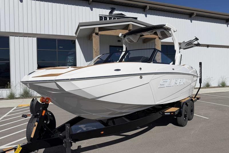 2026 Supra SL boat on trailer, parked outside a modern building.