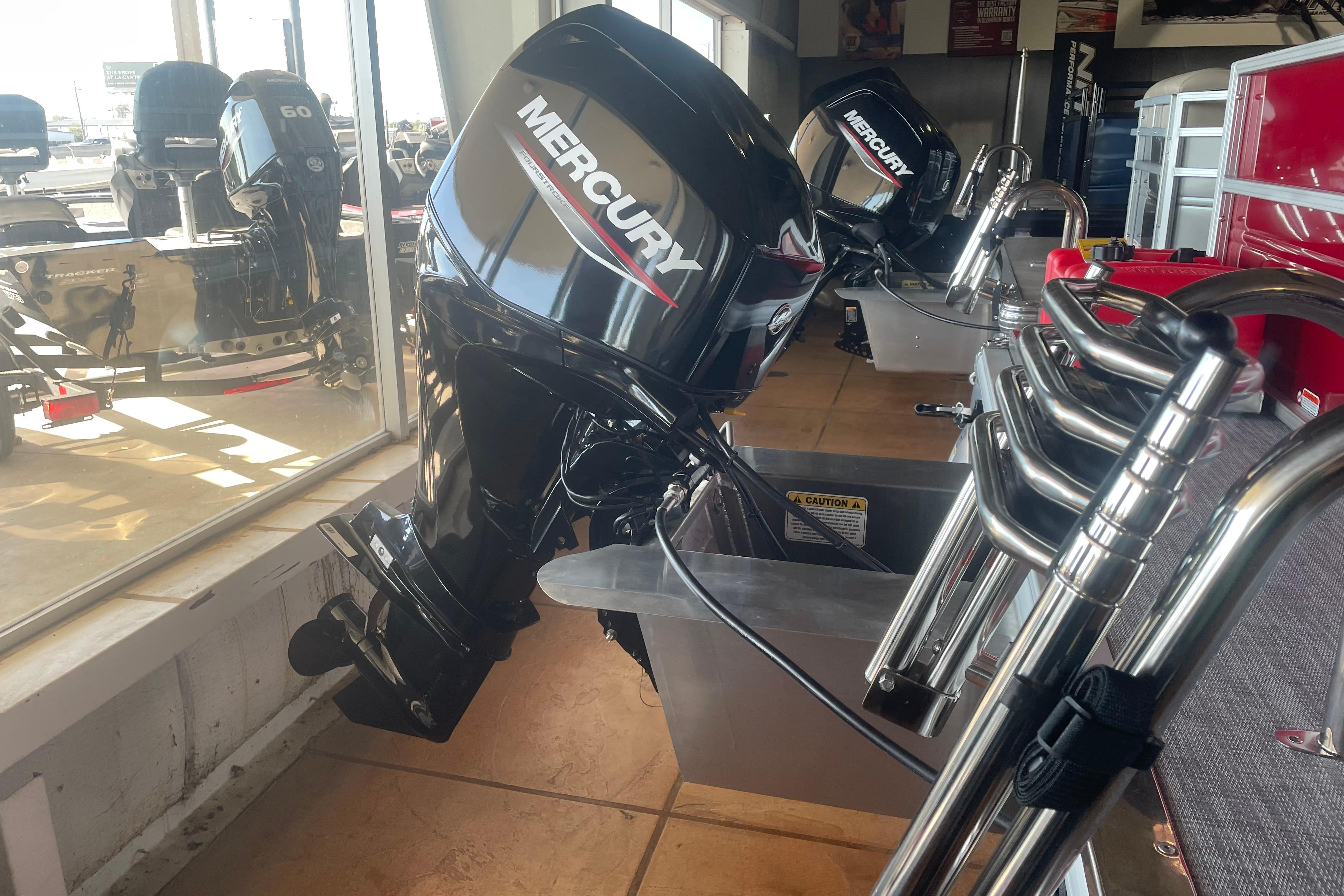2026 Sun Tracker Party Barge 16 DLX with Mercury outboard motor in showroom.
