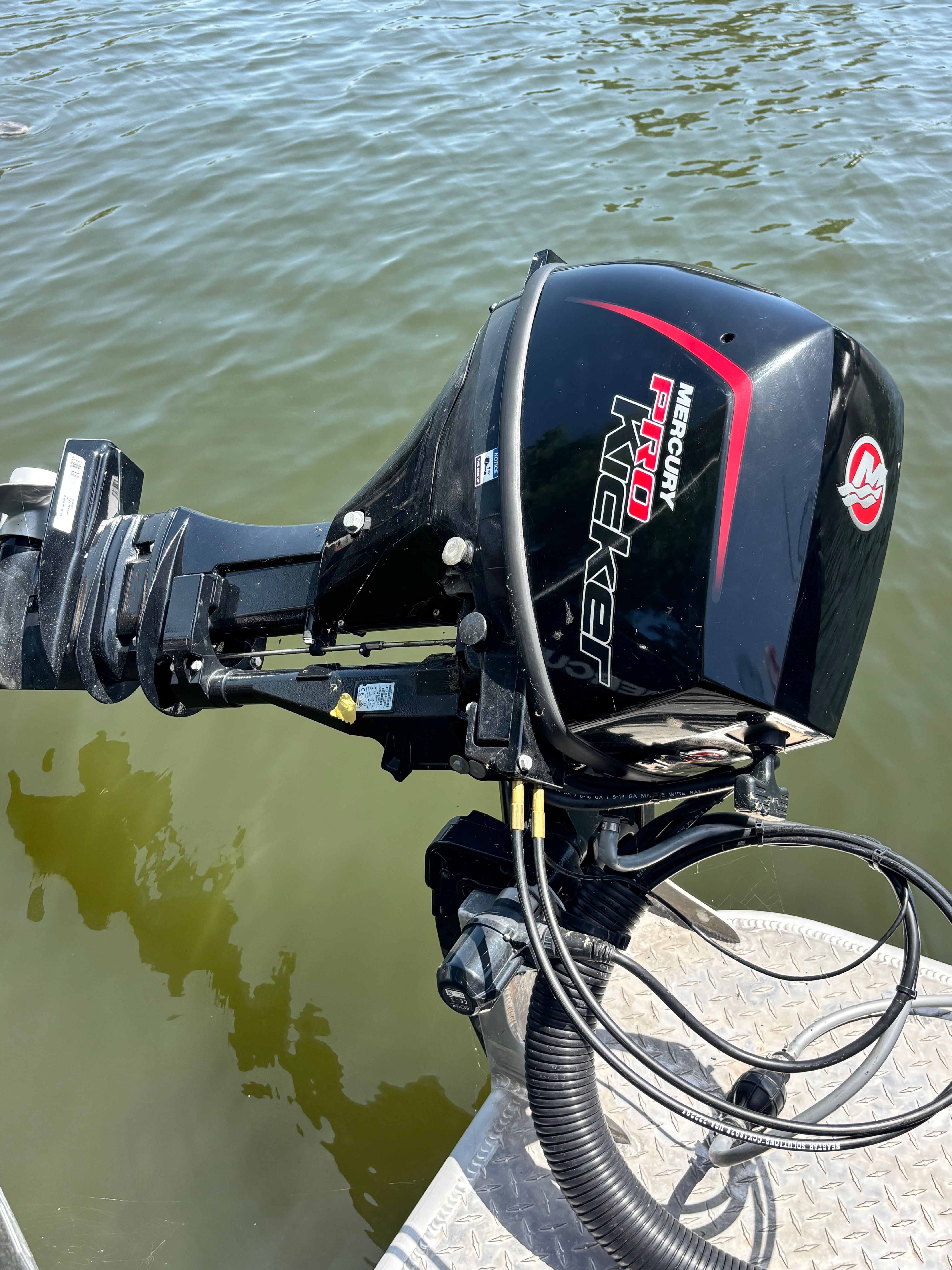 A Mercury Pro outboard motor on a boat, floating on calm water.