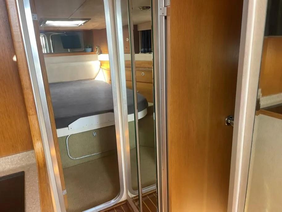 Interior of 1985 Princess Sedan Flybridge yacht with cozy bedroom and wooden finishes.