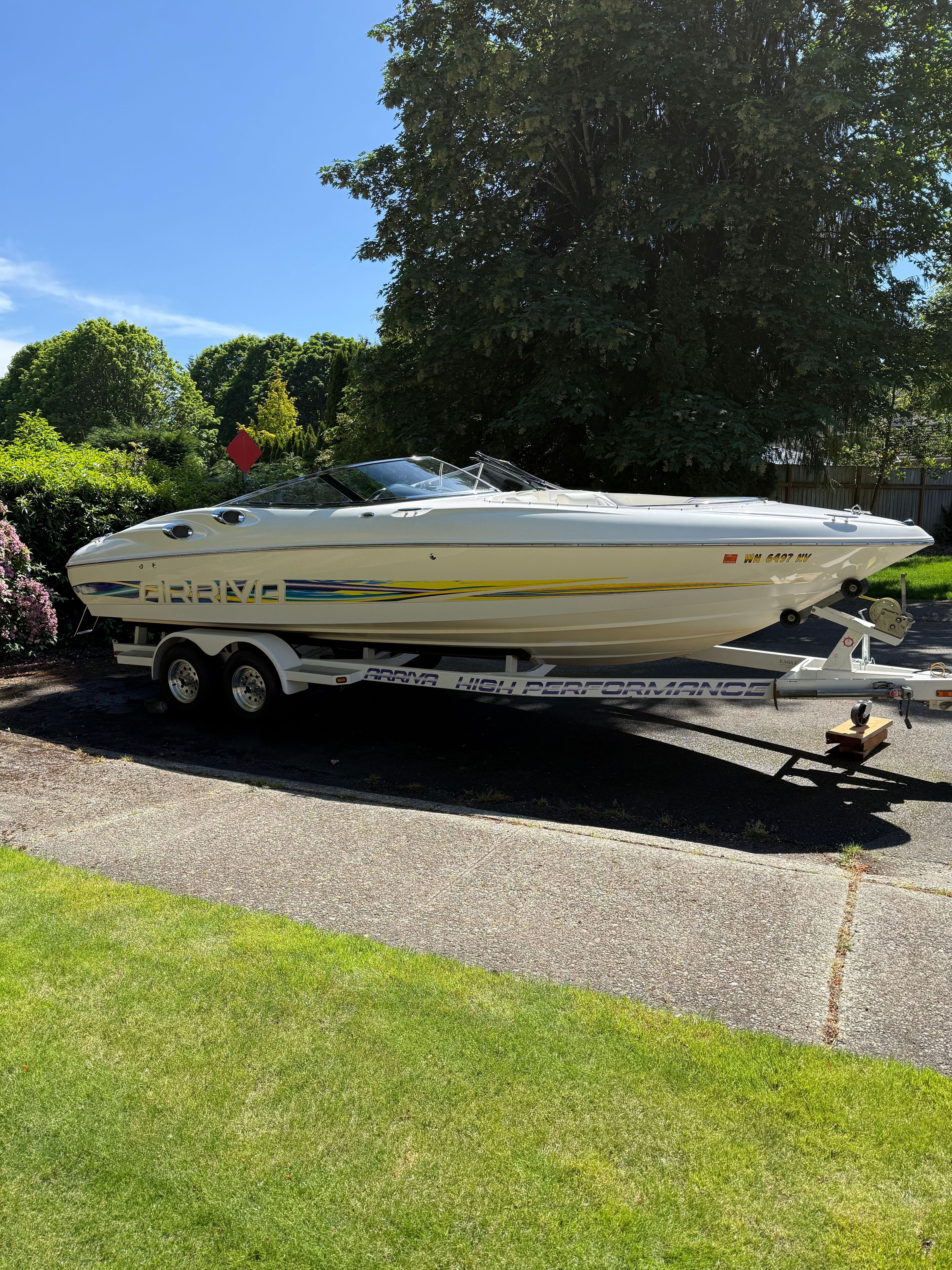 A white motorboat, Arriva 2550 model from 1997, is on a trailer outdoors.
