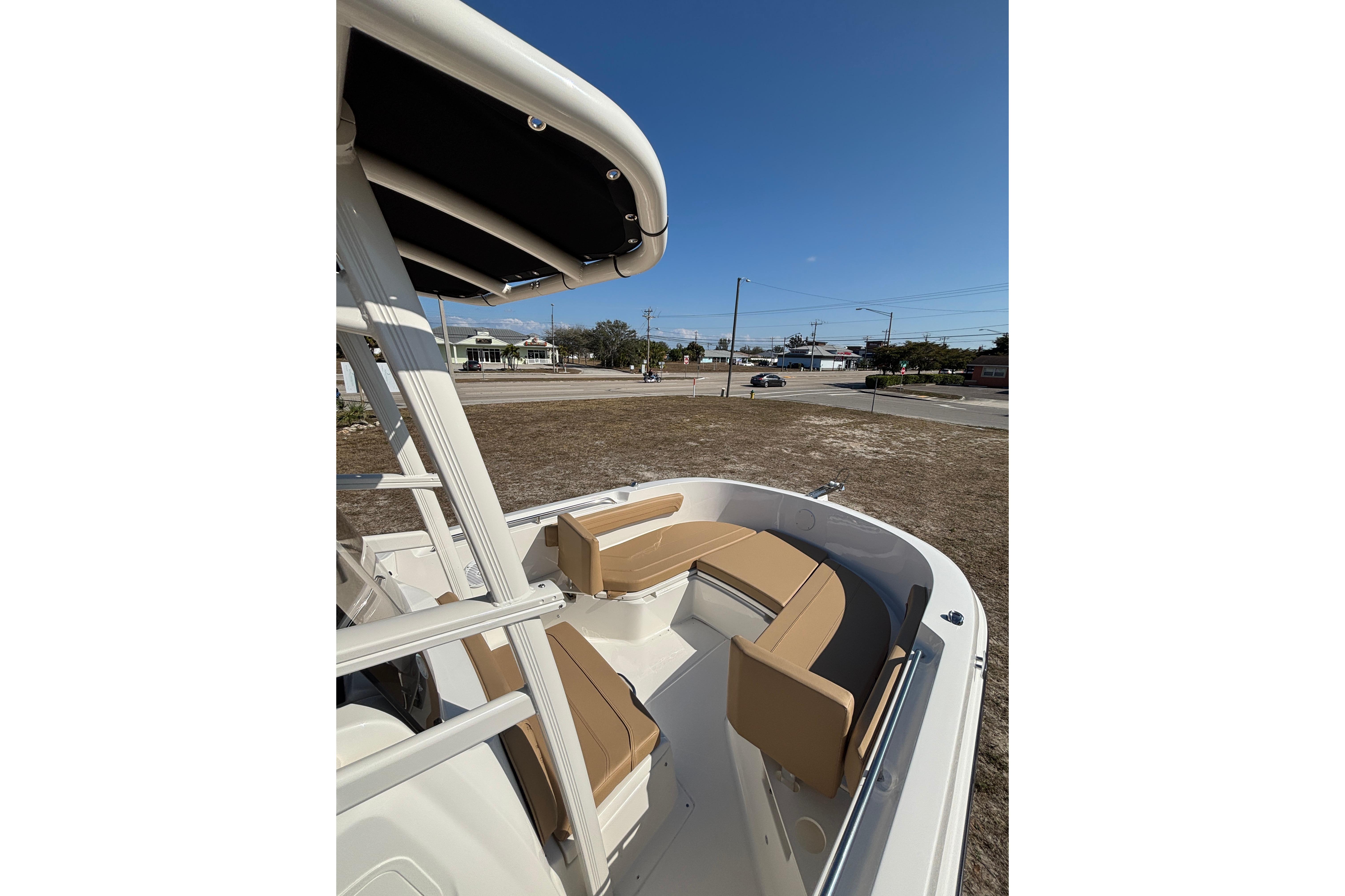 2026 Bayliner Trophy T22CC boat with tan seating and T-top, parked on land.