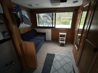 Interior of a boat with a sofa, carpet, and windows looking outside.
