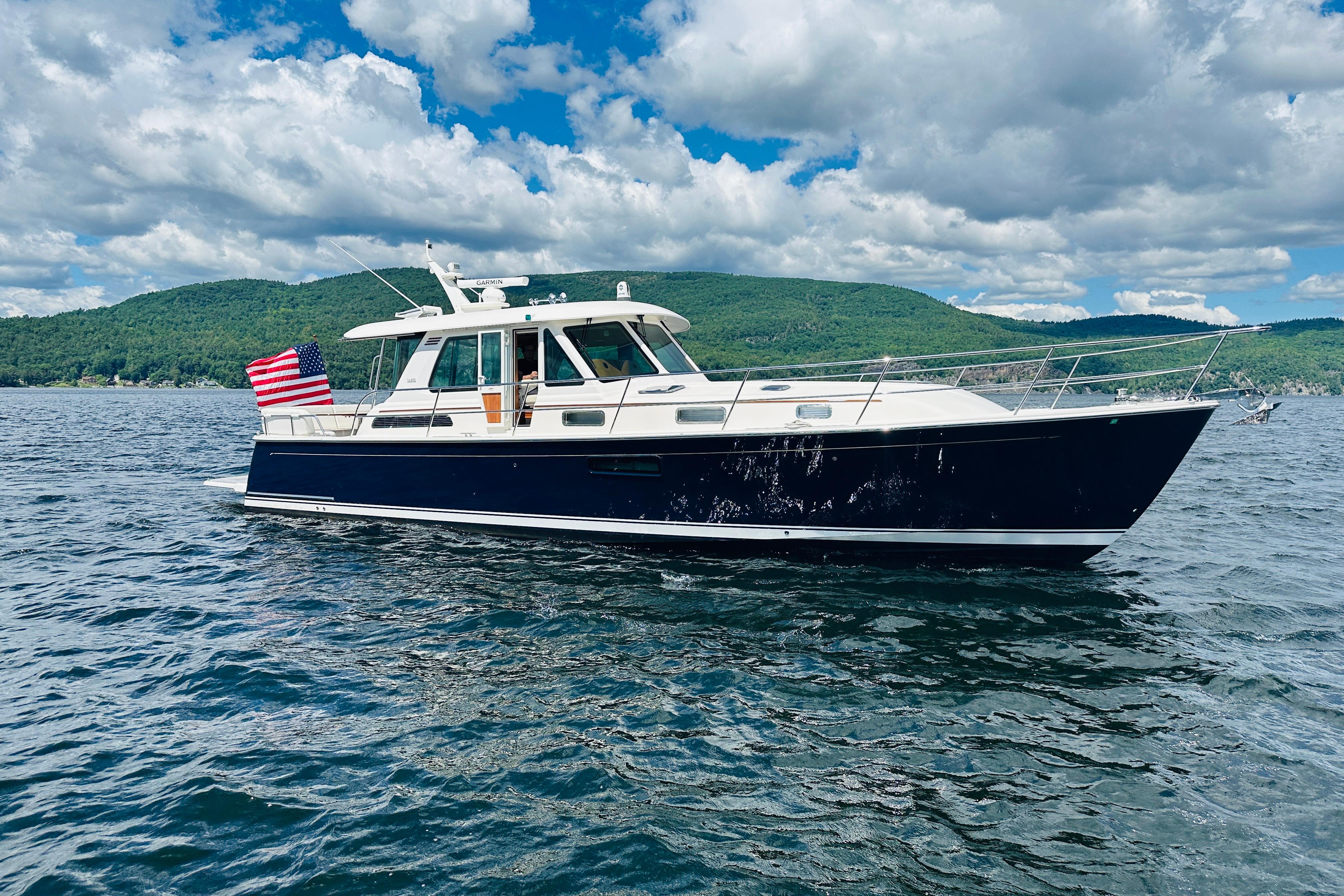 2025 Sabre 48 Salon Express yacht cruising on a scenic lake under a cloudy sky.