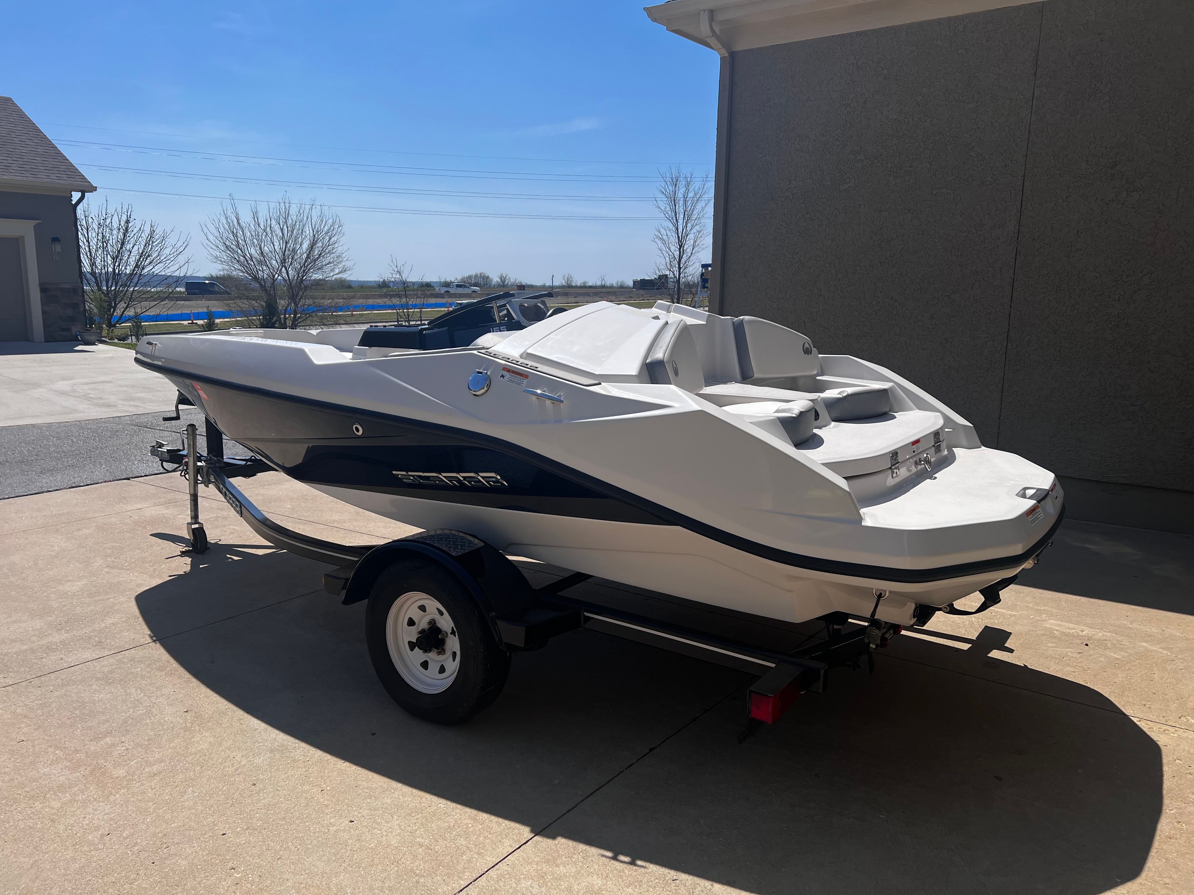 A white 2019 Scarab 165 G boat is on a trailer in a driveway.