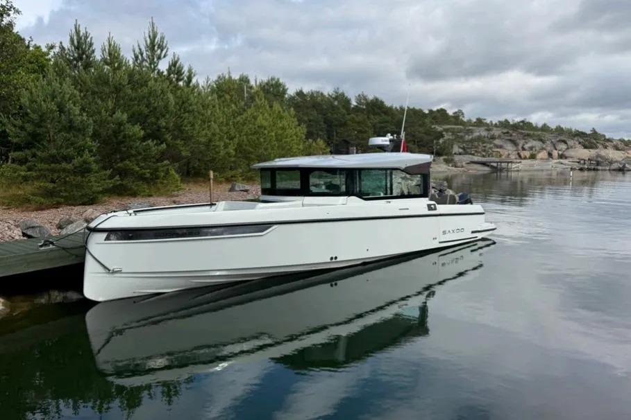 2022 Saxdor 320 GTC boat docked on calm water with scenic forest background.