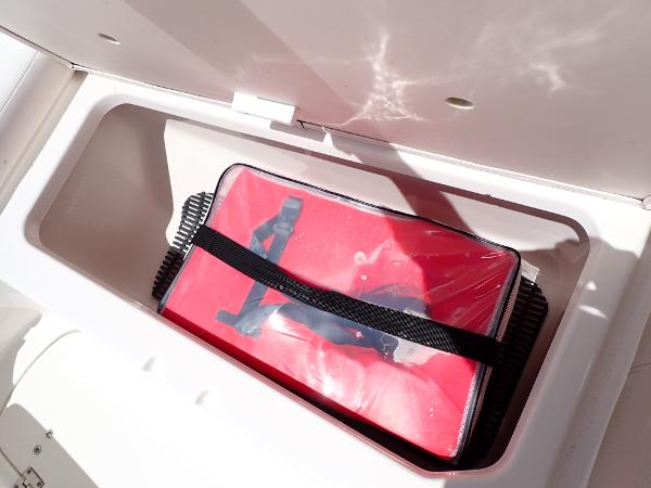 Storage compartment in a 2011 Chaparral 287 SSX boat with a red bag inside.