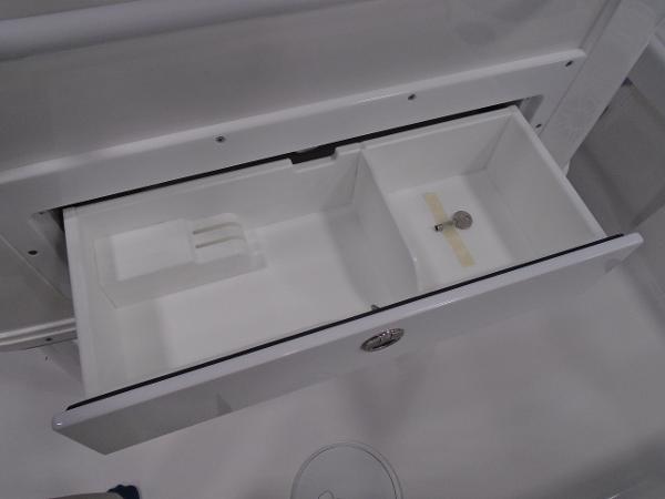 Open storage compartment on 2025 Caymas 26 HB boat, showcasing interior design and functionality.