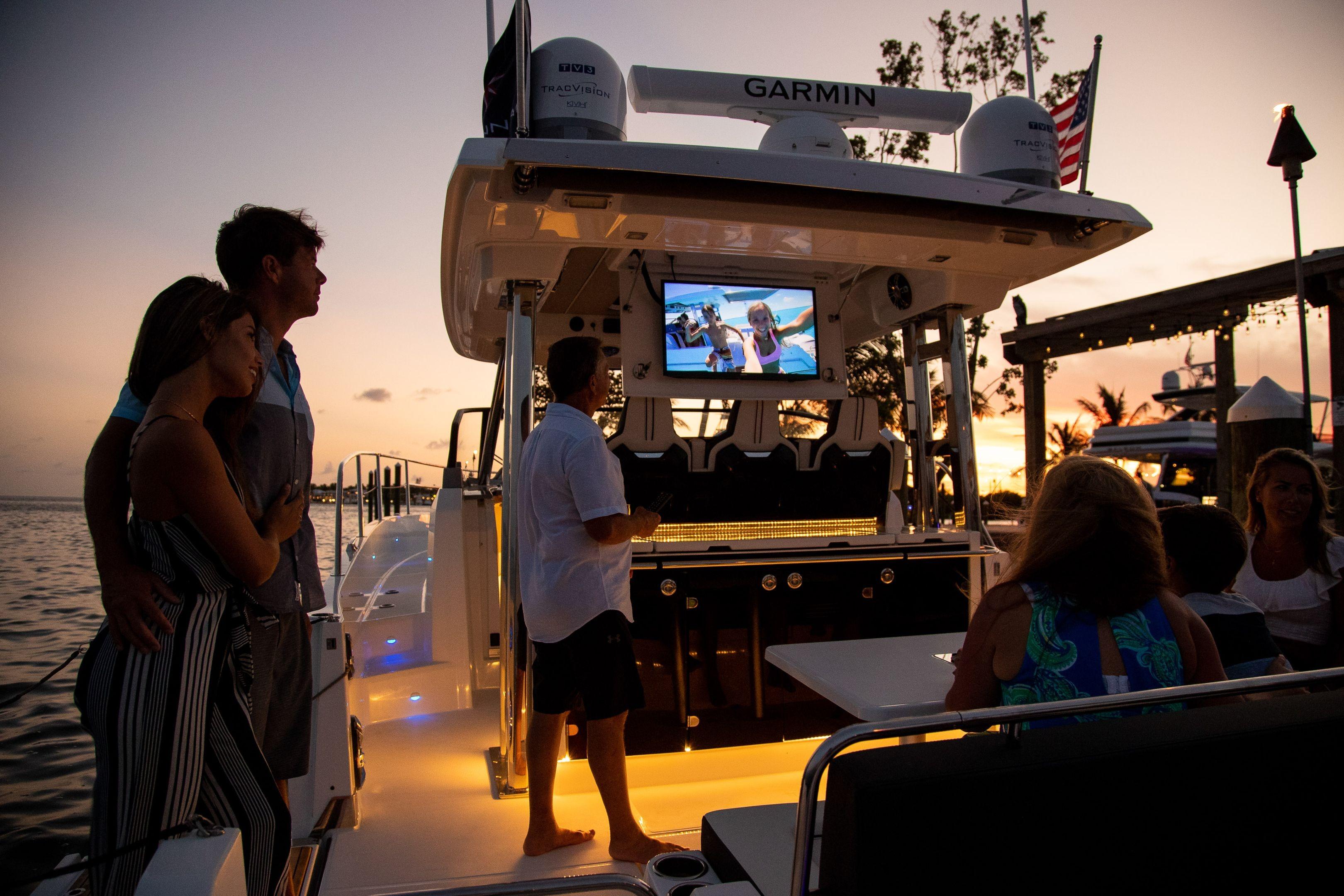 People enjoying sunset on a 2026 Jeanneau Leader 12.5 WA yacht with outdoor entertainment.