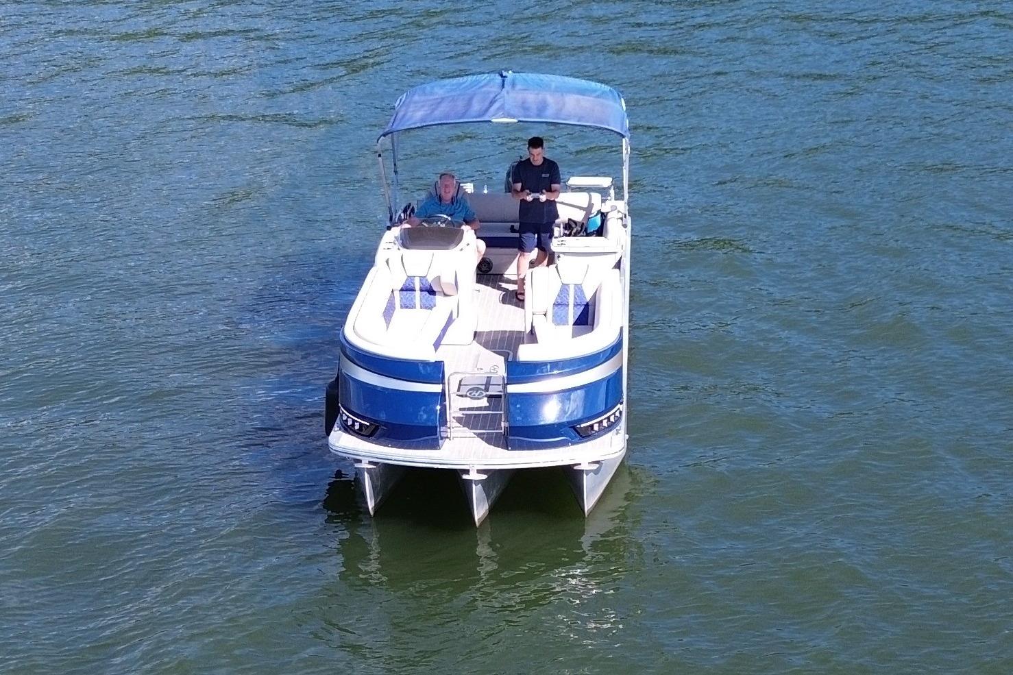 2022 Harris Grand Mariner 250 pontoon boat on water, featuring blue canopy and seating.