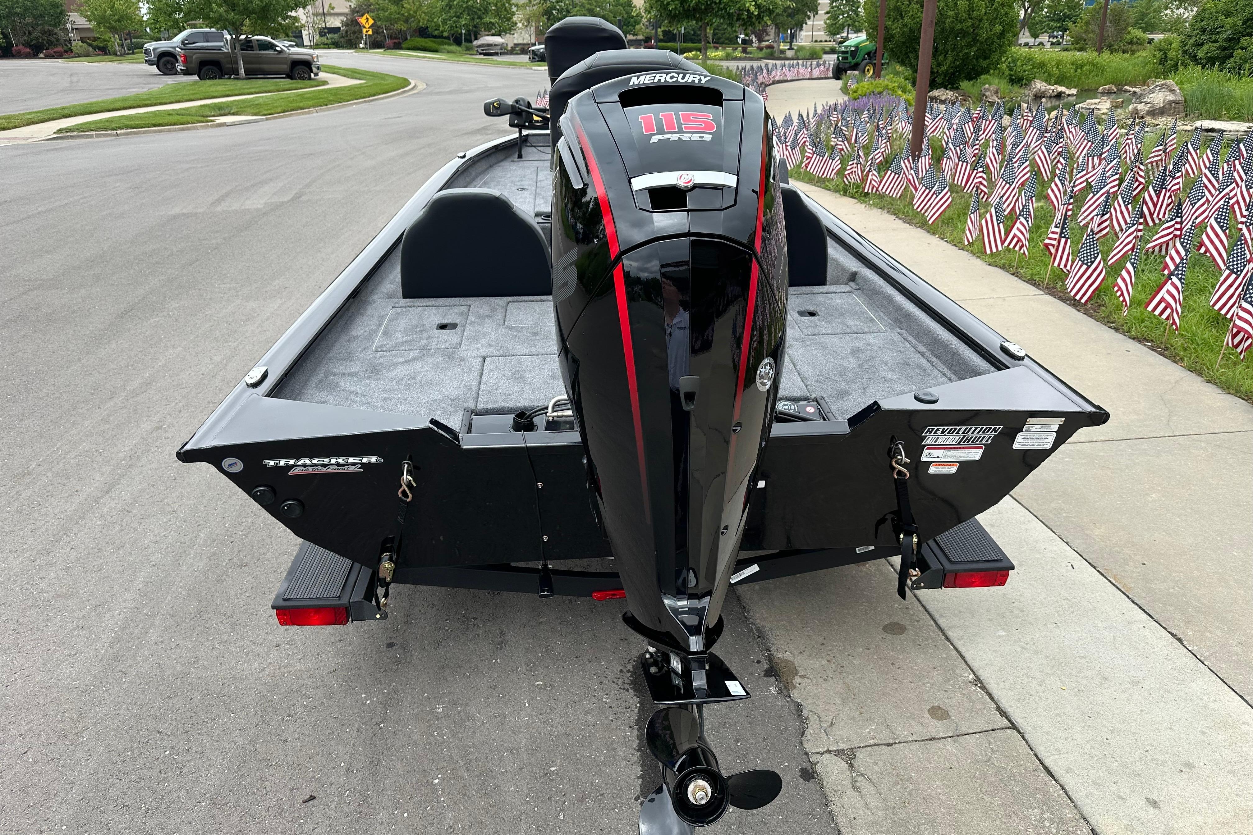 2026 Tracker Pro Team 190 boat with Mercury 115 engine, parked near American flags.