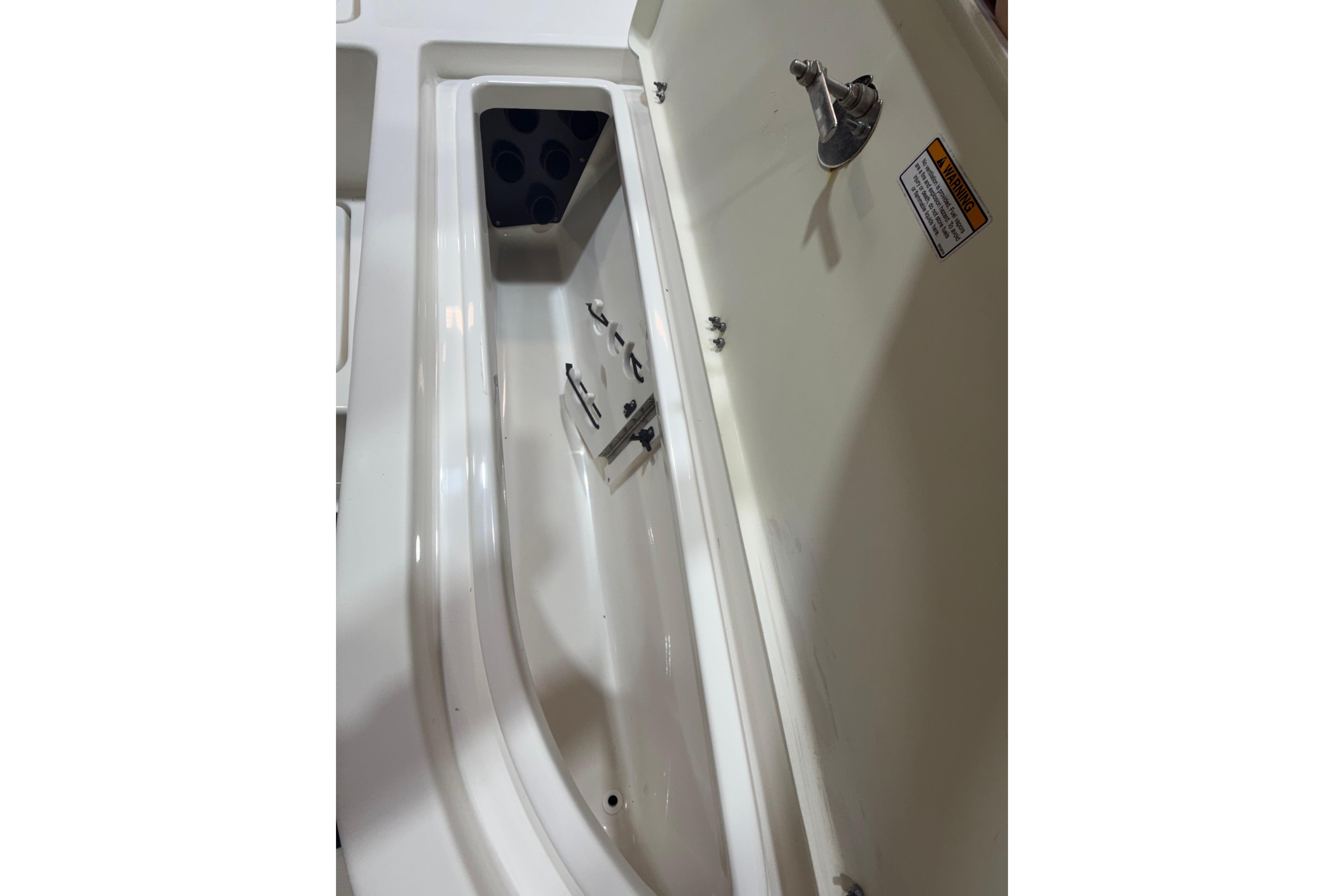 2023 NauticStar 215 XTS boat storage compartment with latch and warning label.