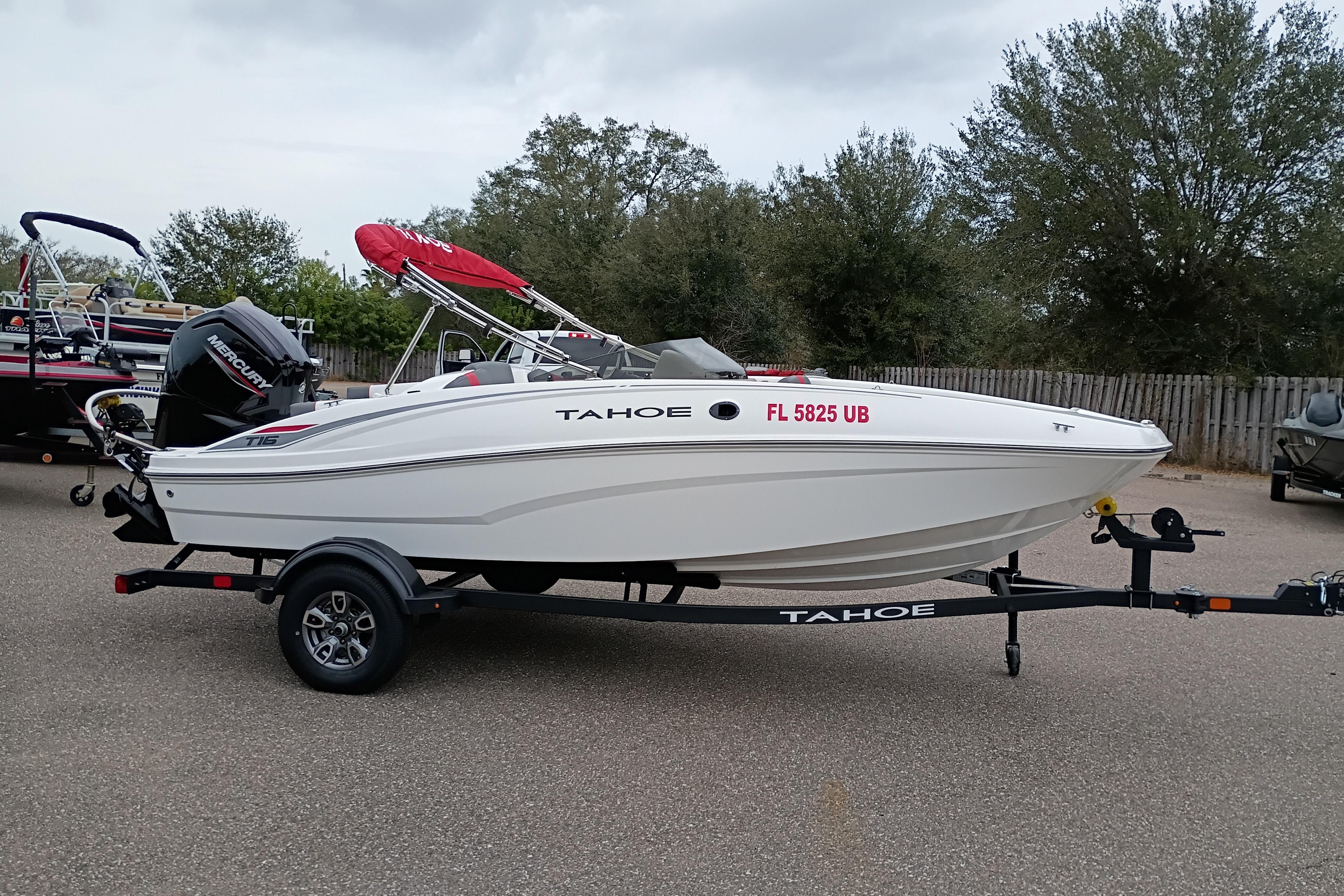 2026 Tahoe T16 boat with trailer, parked outdoors, featuring a red canopy and Mercury engine.