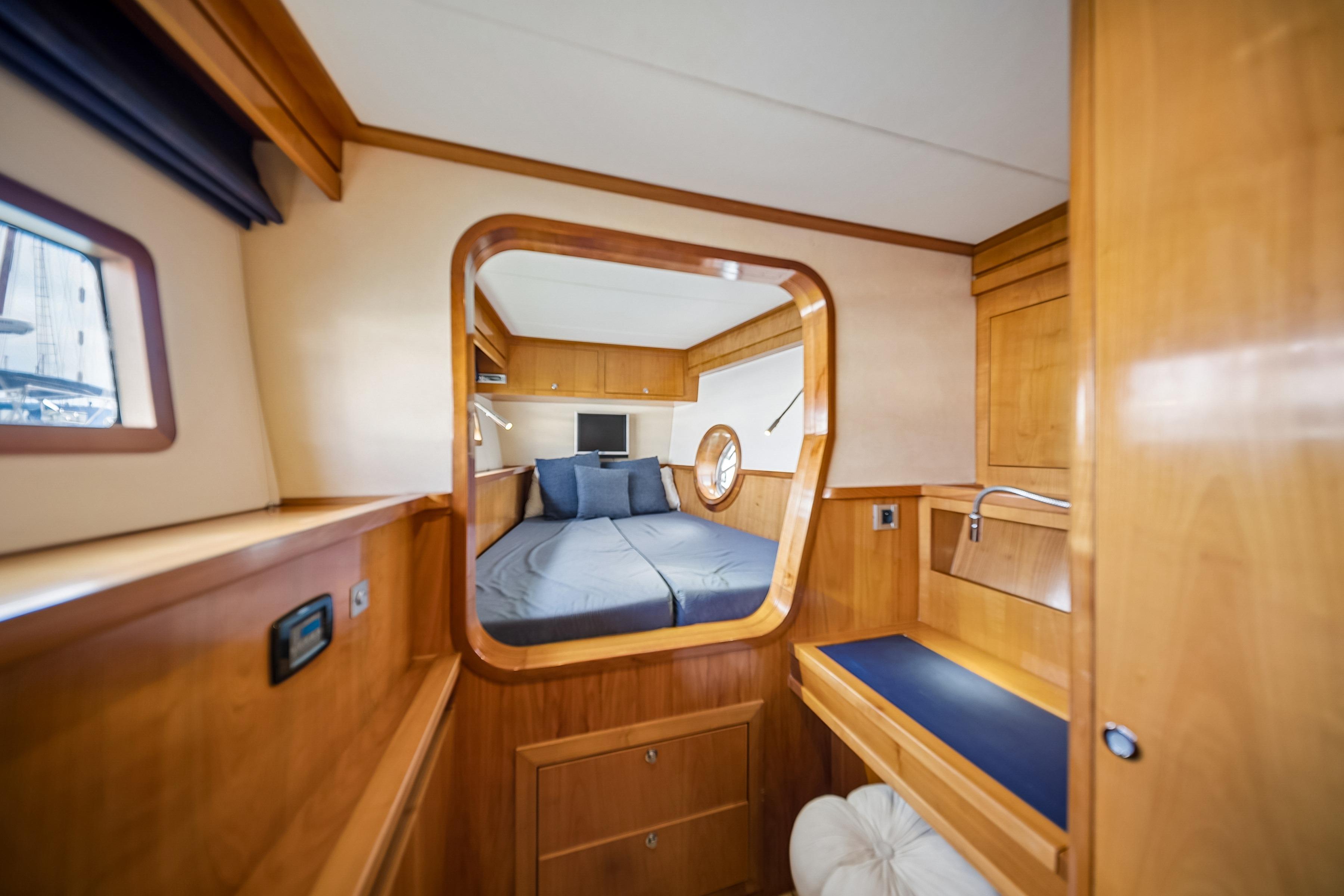 Luxurious interior of 2009 Catana 65 yacht with cozy bedroom and wooden furnishings.