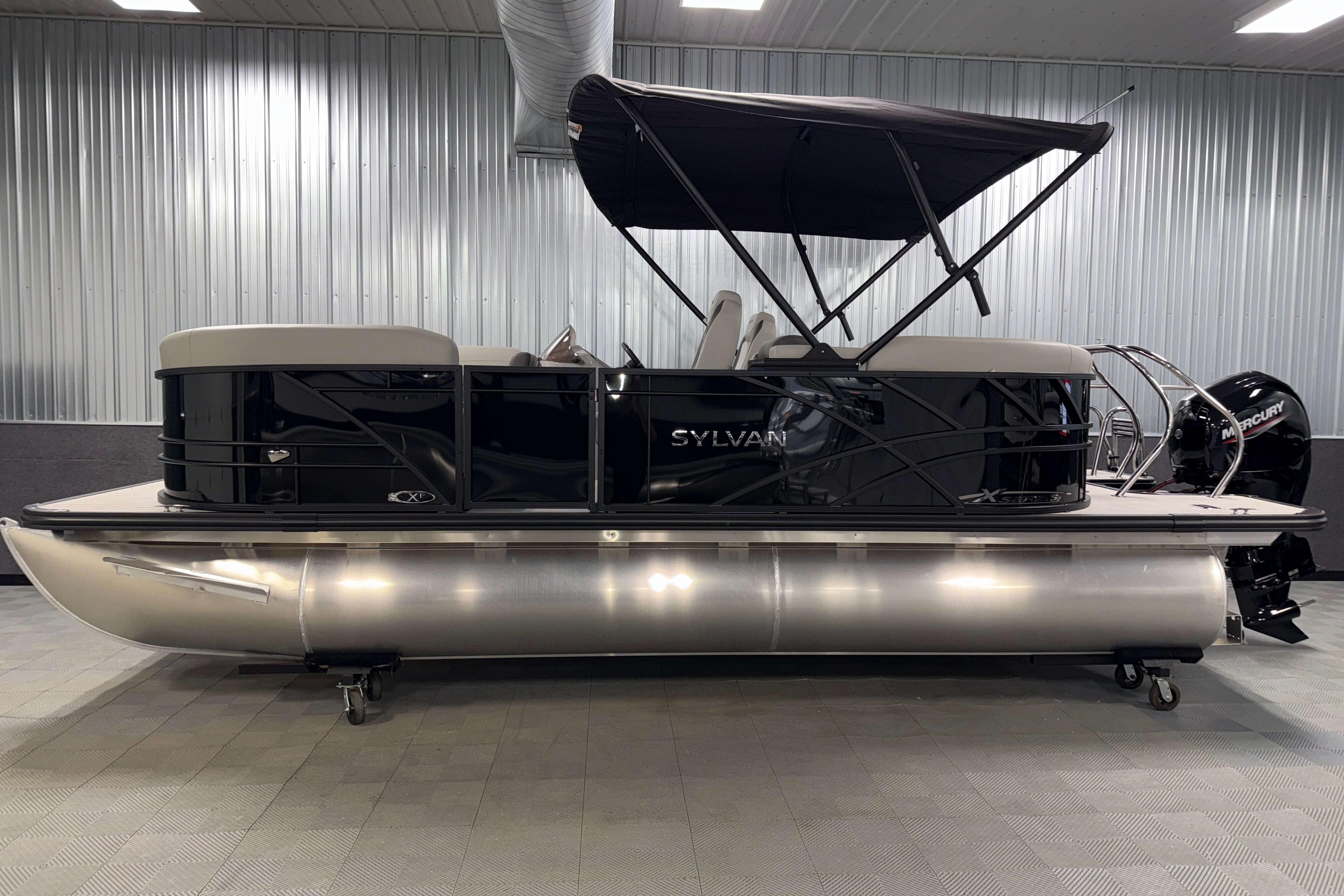 2026 Sylvan Mirage X1 pontoon boat with sleek black design in a showroom setting.