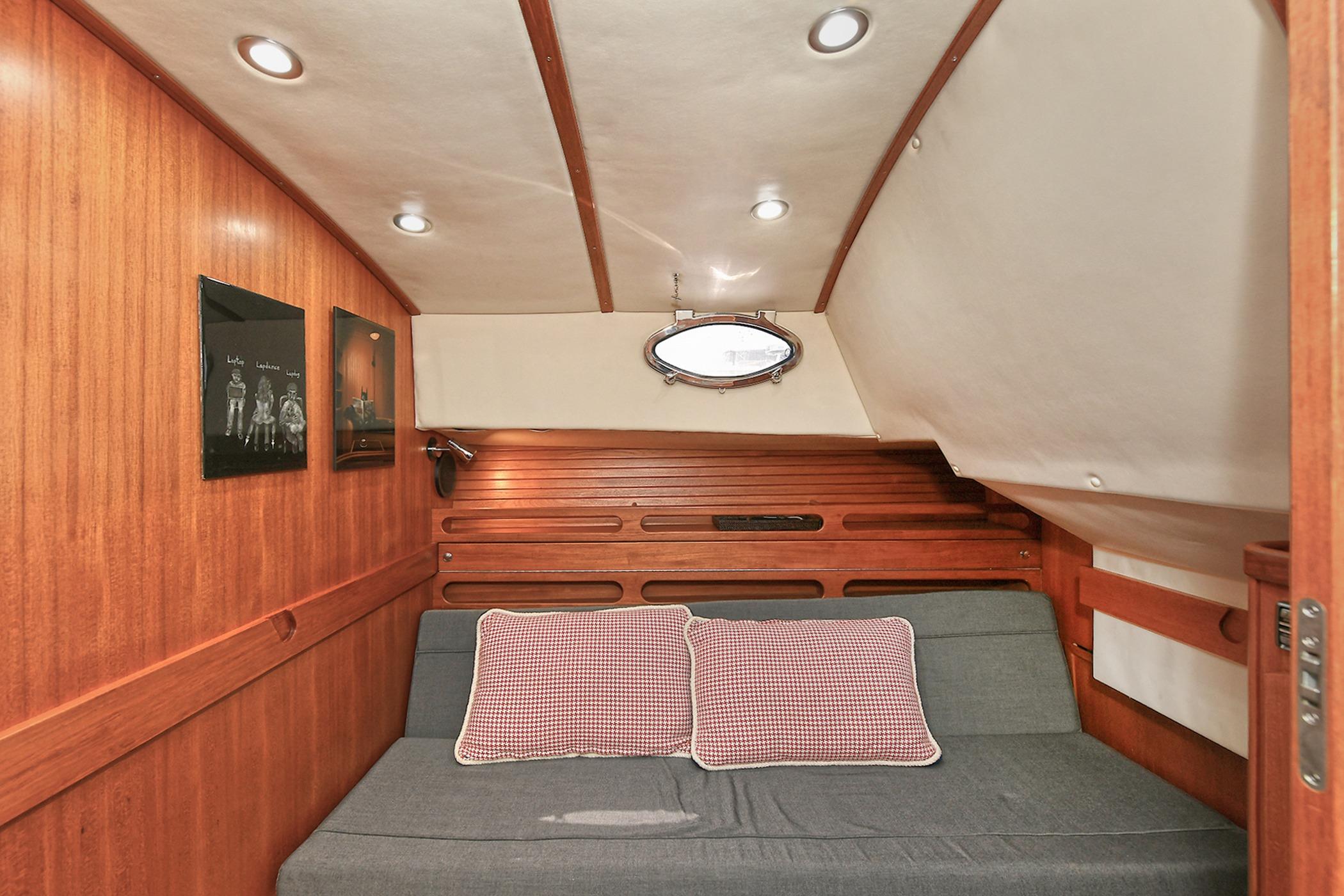 Cozy cabin interior of 2005 San Juan Downeast Express with wood paneling and sofa.