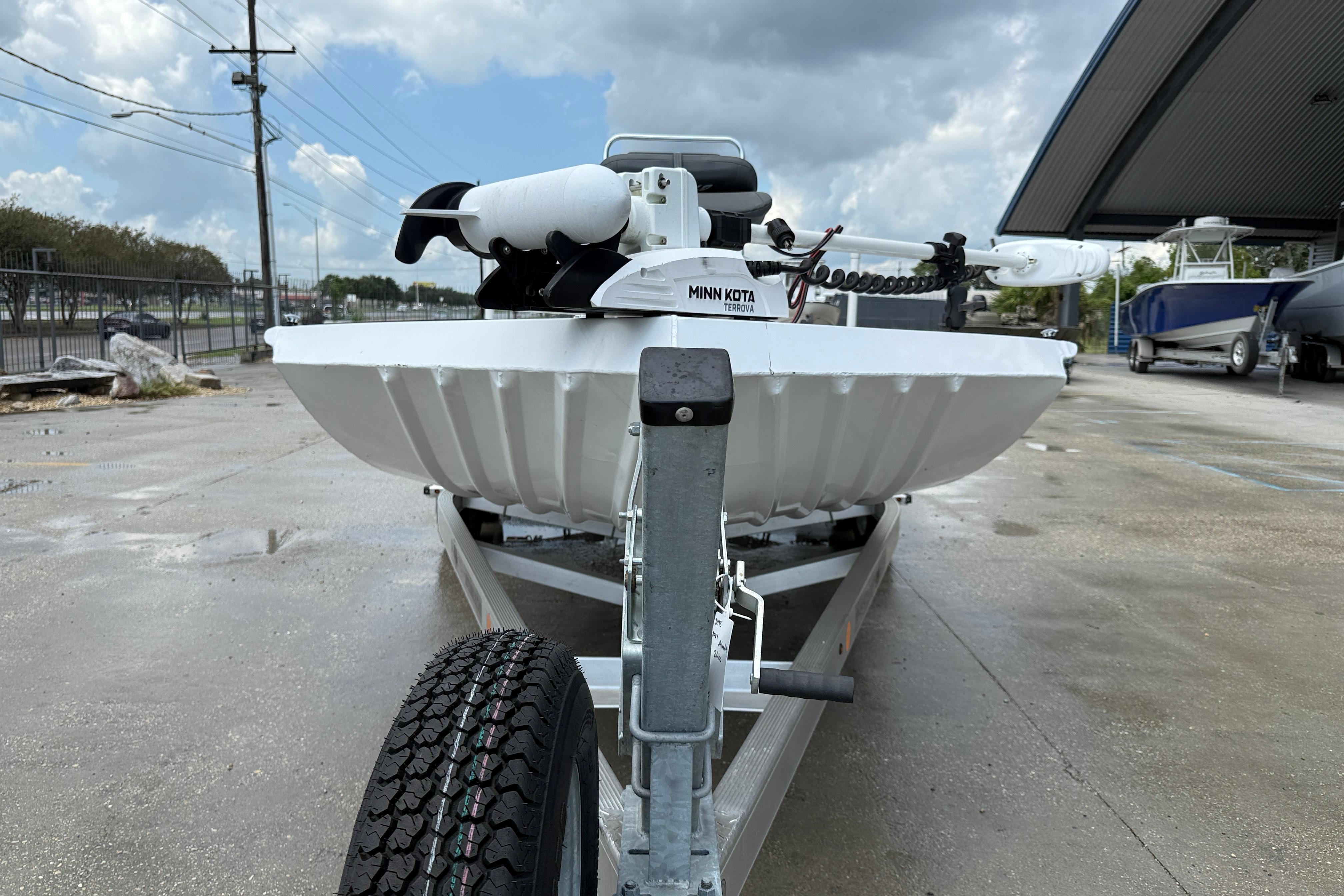 2024 Alweld 2070cc boat on trailer with Minn Kota motor, parked outdoors.