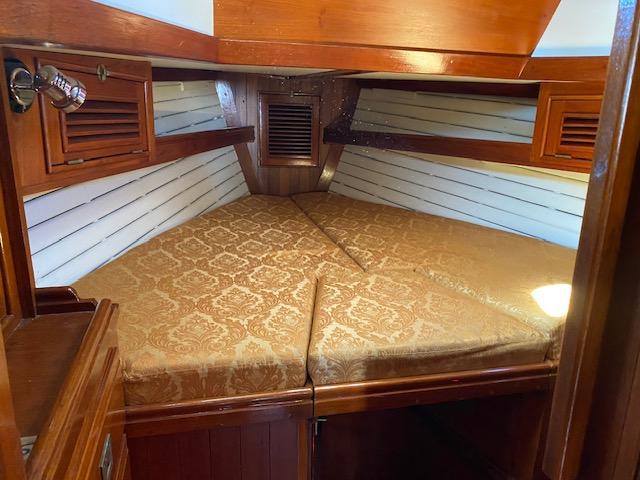 Cozy cabin interior of 1988 Shannon 43 sailboat with elegant wood finish and patterned bedding.