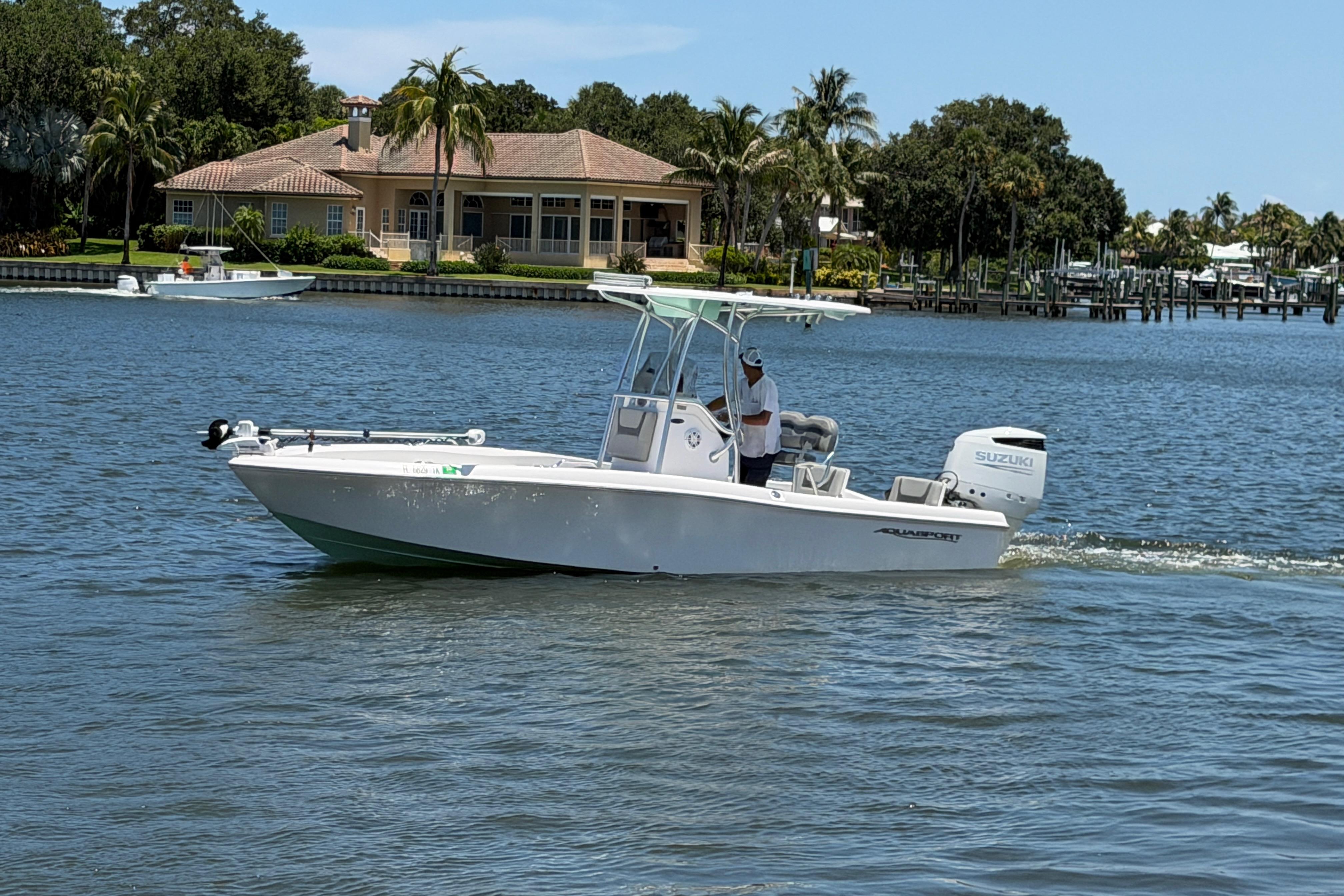 2022 Aquasport 230 Pro Bay boat cruising on a scenic waterway.