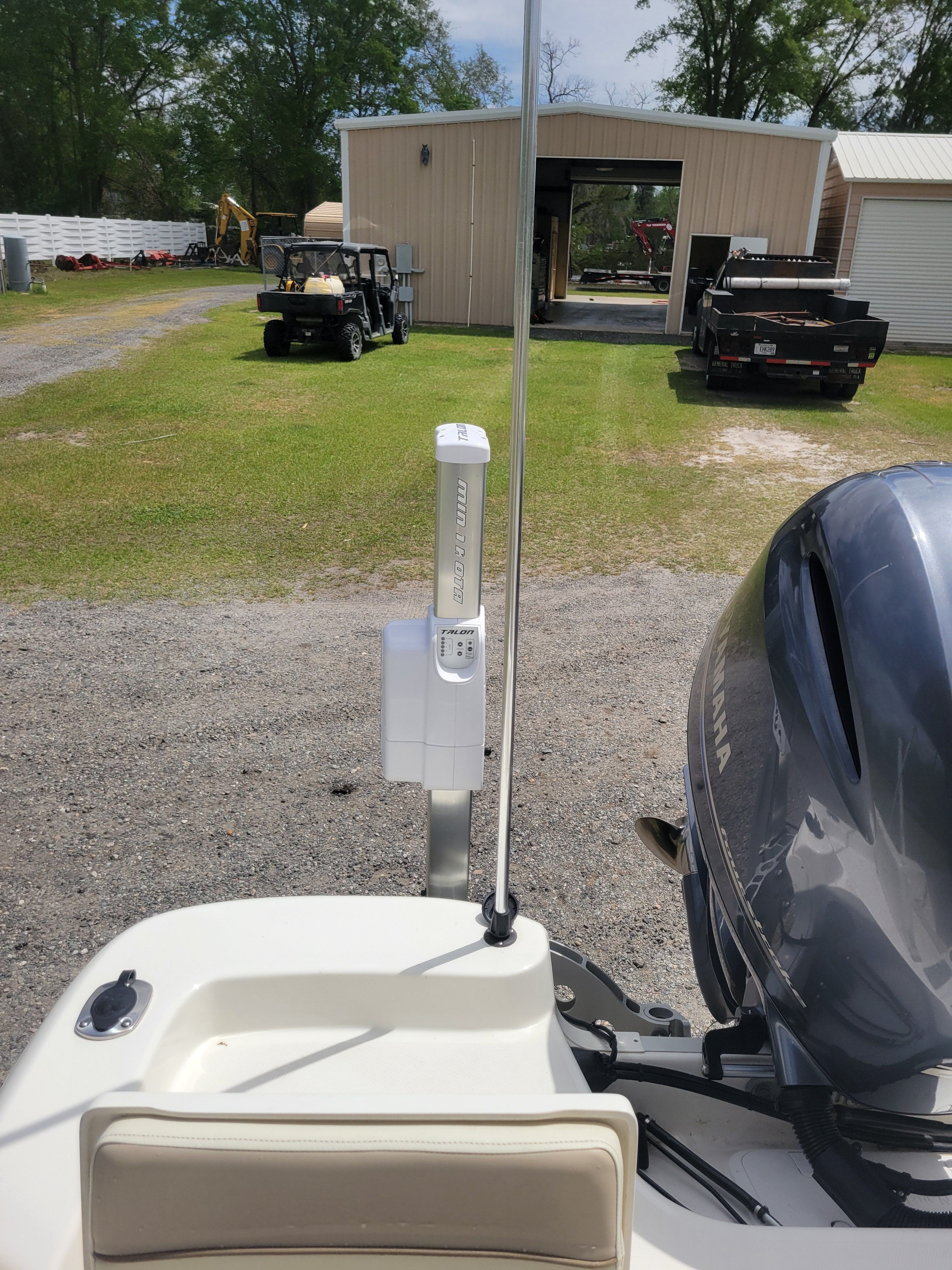A boat with a Yamaha engine is on a gravel path in front of a garage.