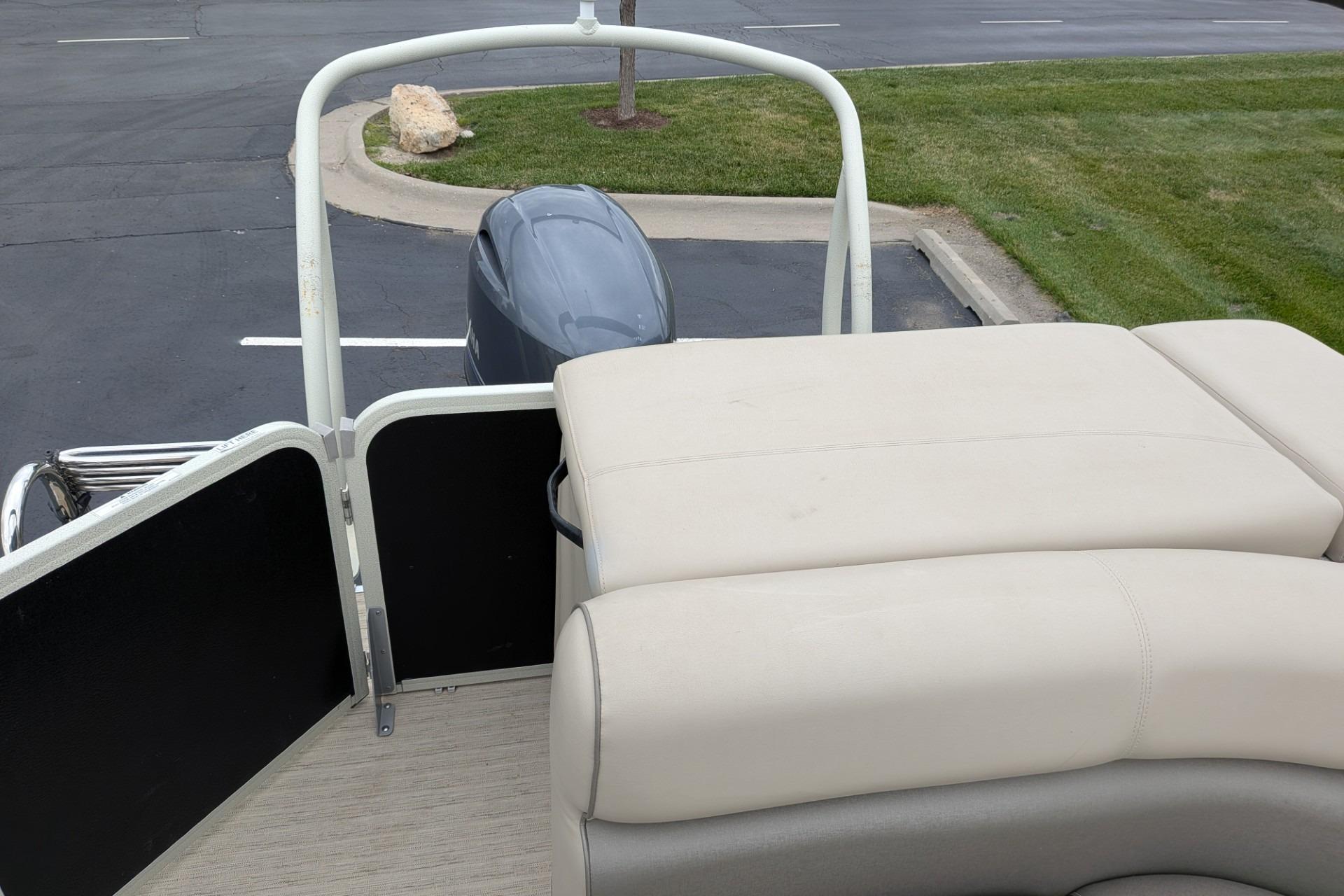 2018 Premier 220 SunSation boat with beige seating and outboard motor, parked on pavement.