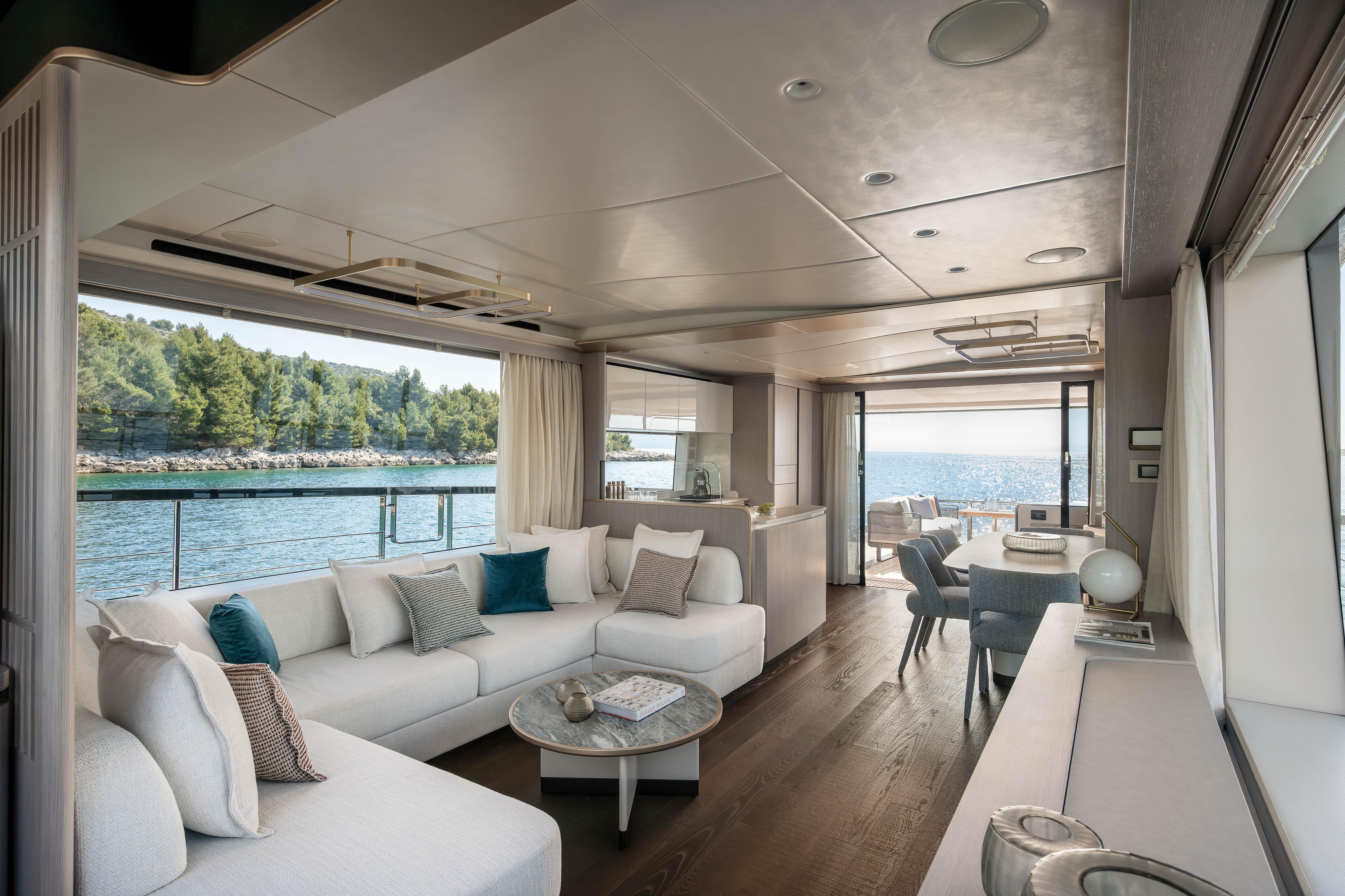 Luxurious yacht interior with white sofas and a sea view.