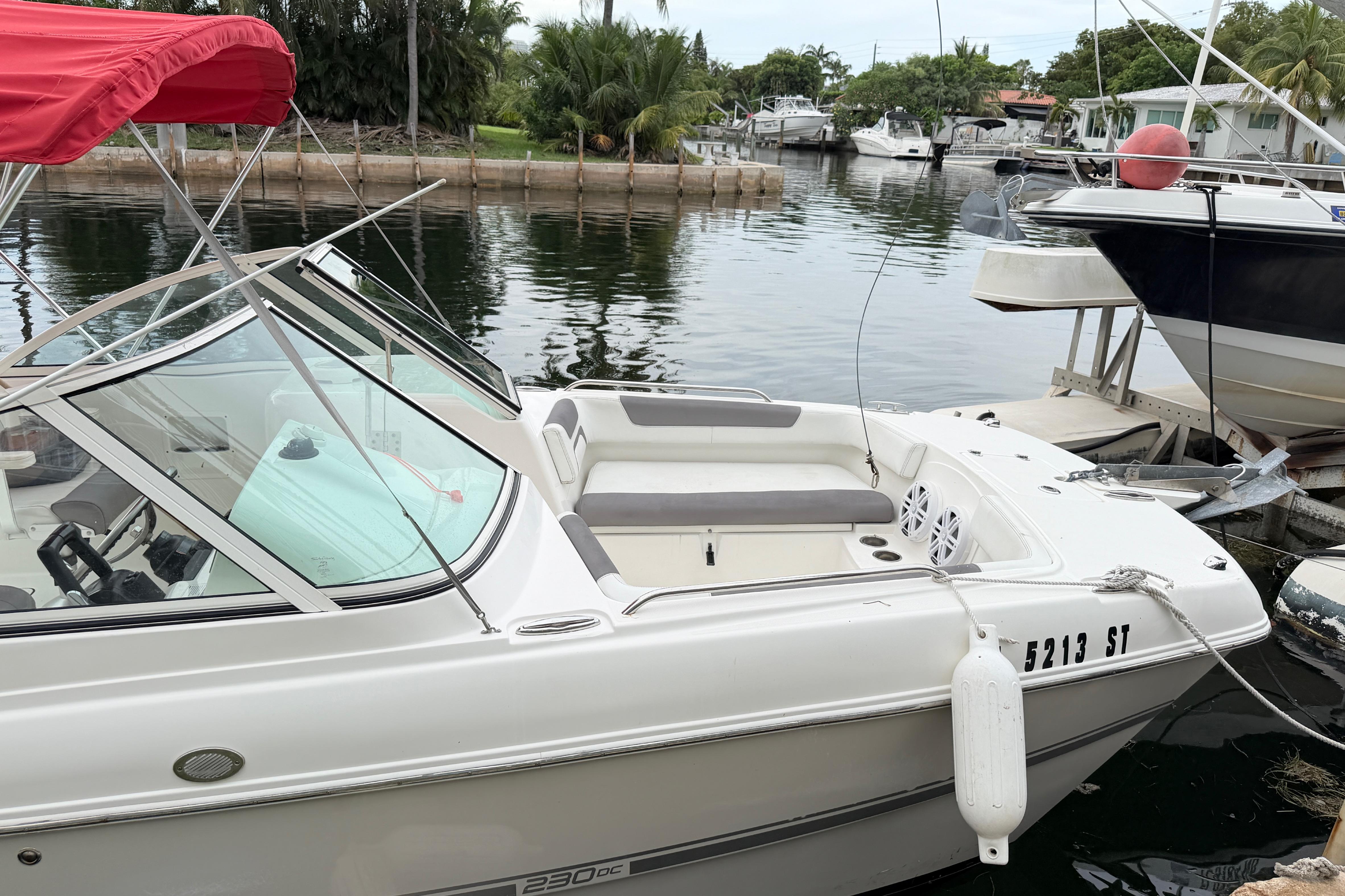 2019 World Cat 230 DC boat docked with red canopy, in a serene marina setting.