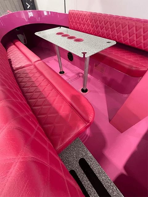 2023 Vision Marine Fantail 217 interior with vibrant pink seating and sleek table design.