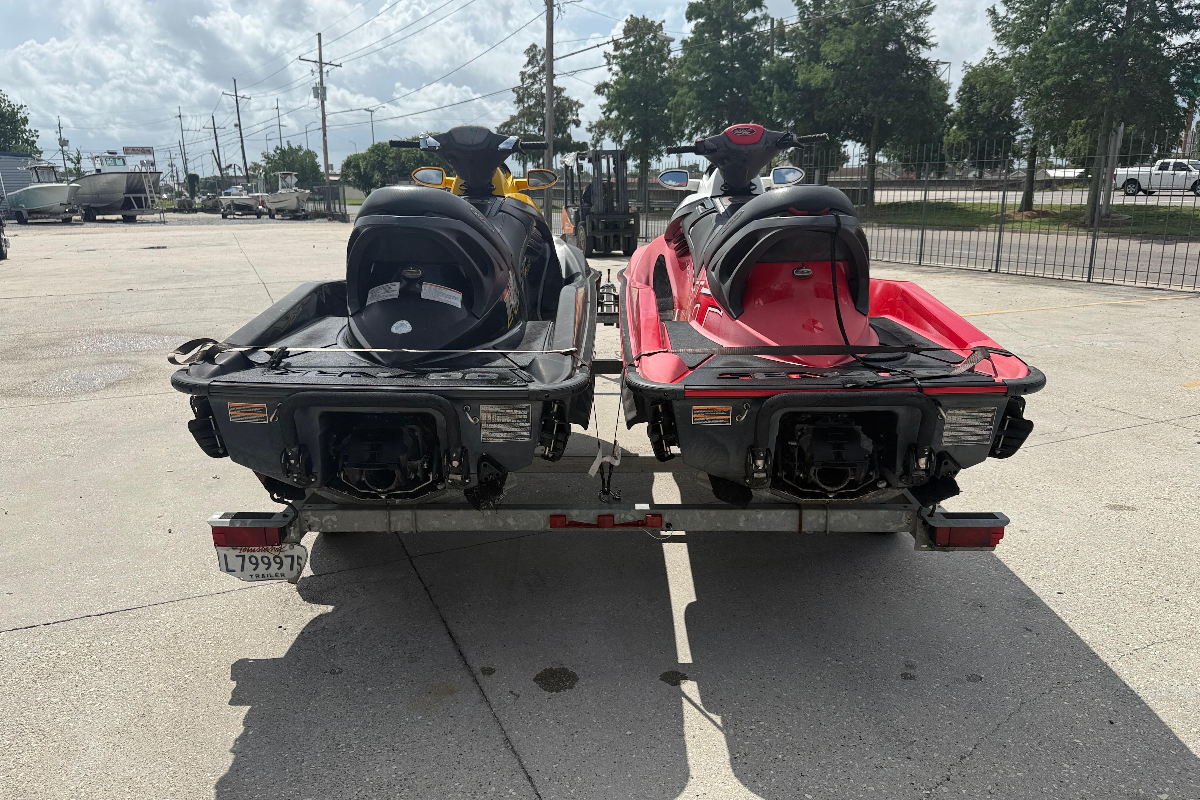 Two 2007 Sea-Doo RXT 215 jet skis on a trailer in a parking lot.