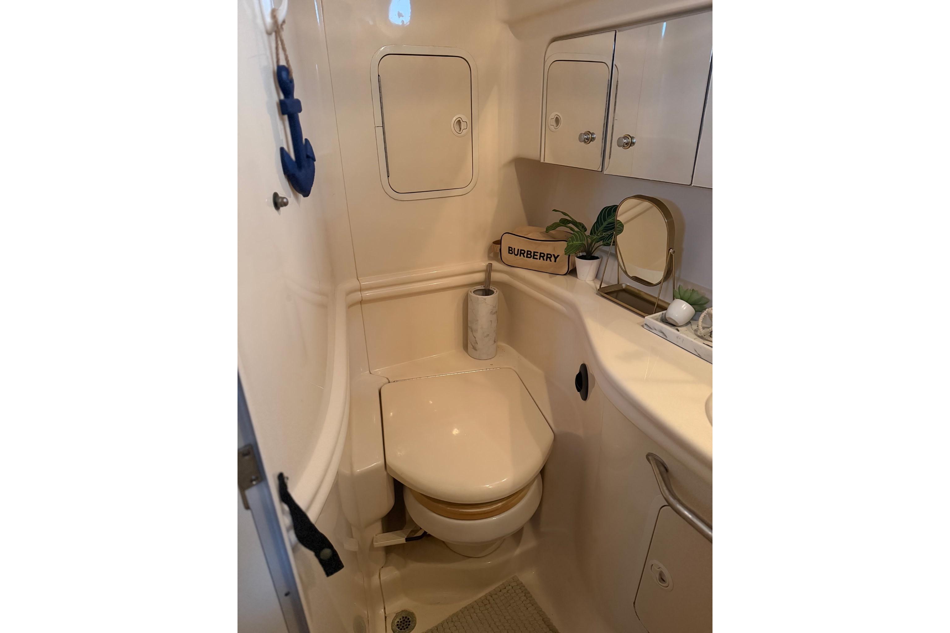 2002 Sea Ray Sundancer 320 bathroom with toilet, mirror, and storage cabinets.