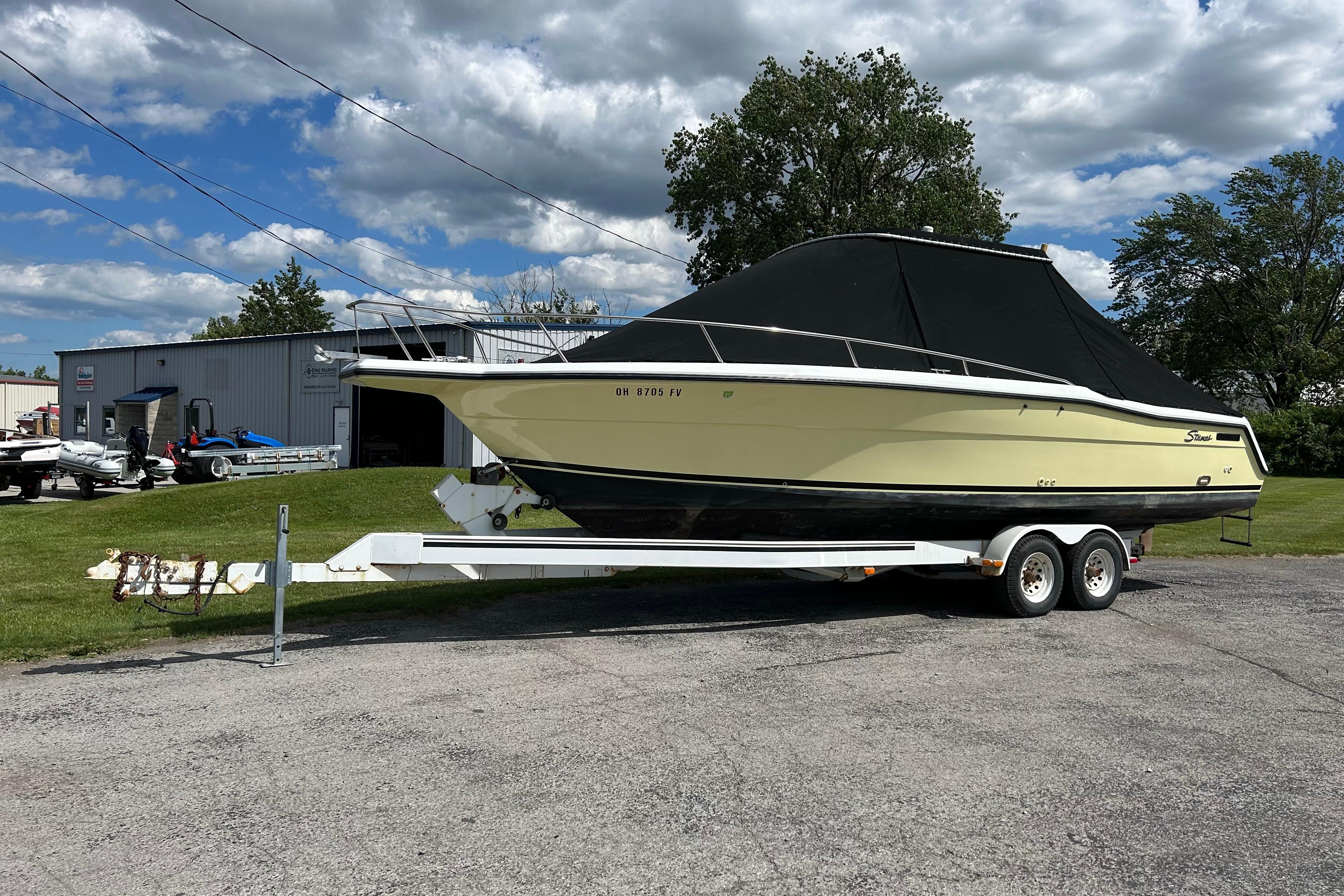 1997 Stamas 290 Tarpon boat on trailer, parked outdoors under a cloudy sky.