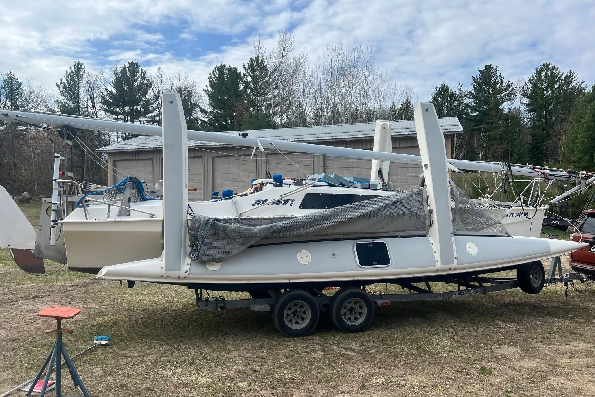 1993 Corsair F-27 sailboat on trailer, parked outdoors near trees and a building.