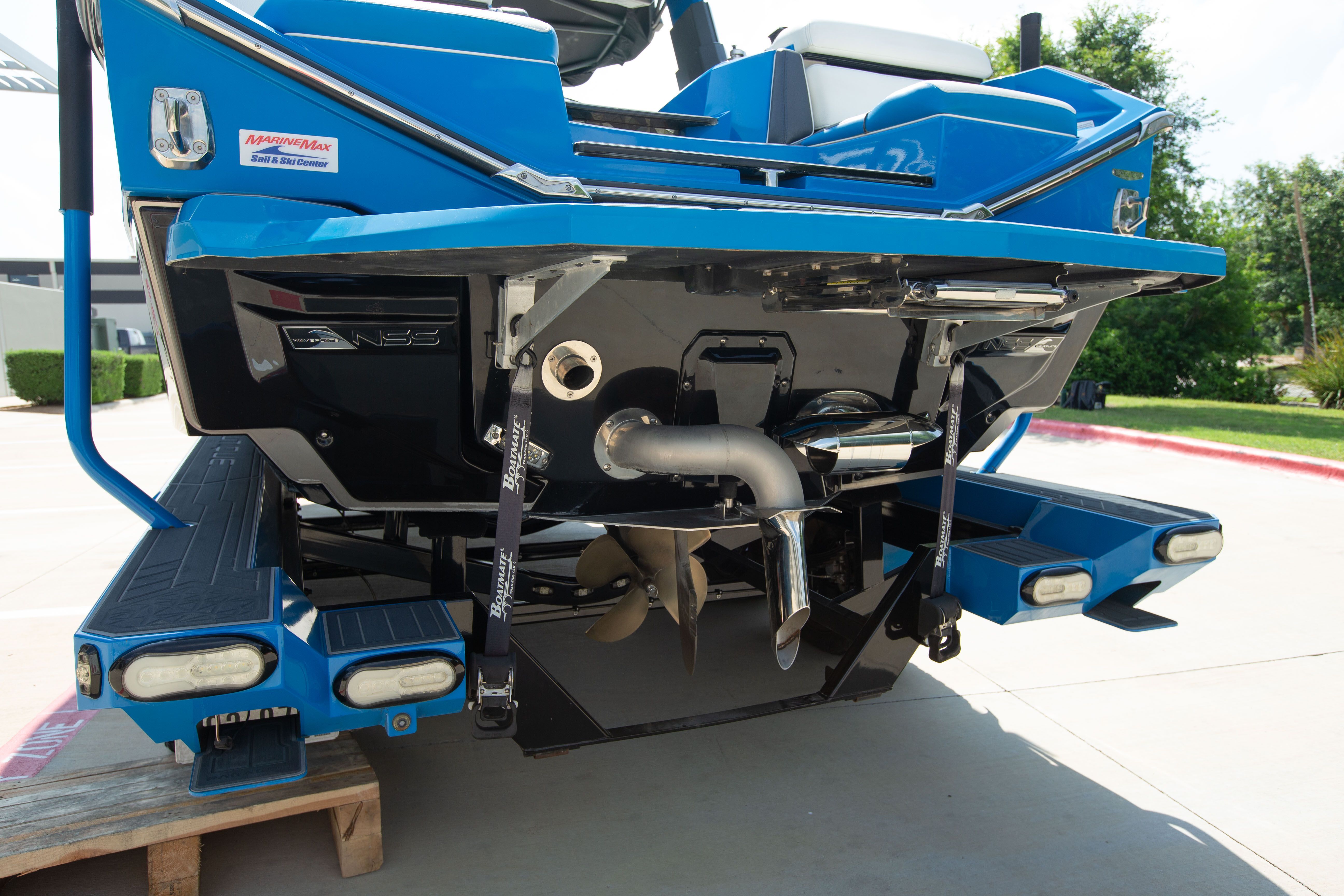 The rear of a blue boat with propeller and exhaust system.