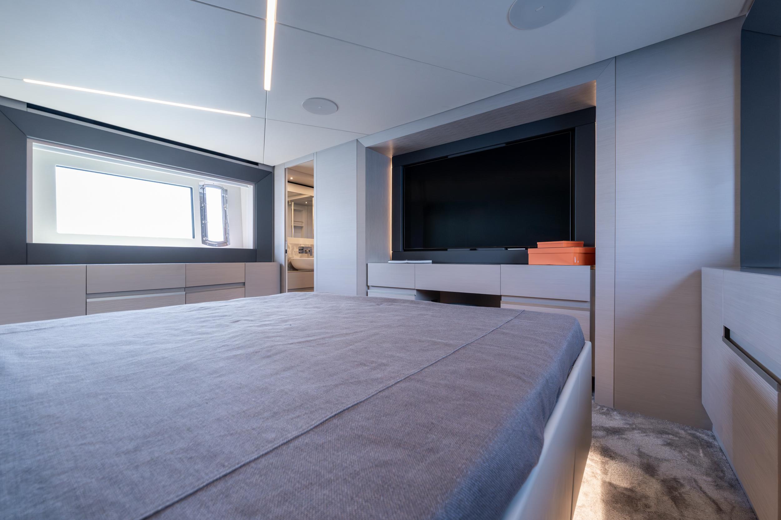 Luxurious interior of 2024 Pershing 7X yacht bedroom with modern design and large TV.