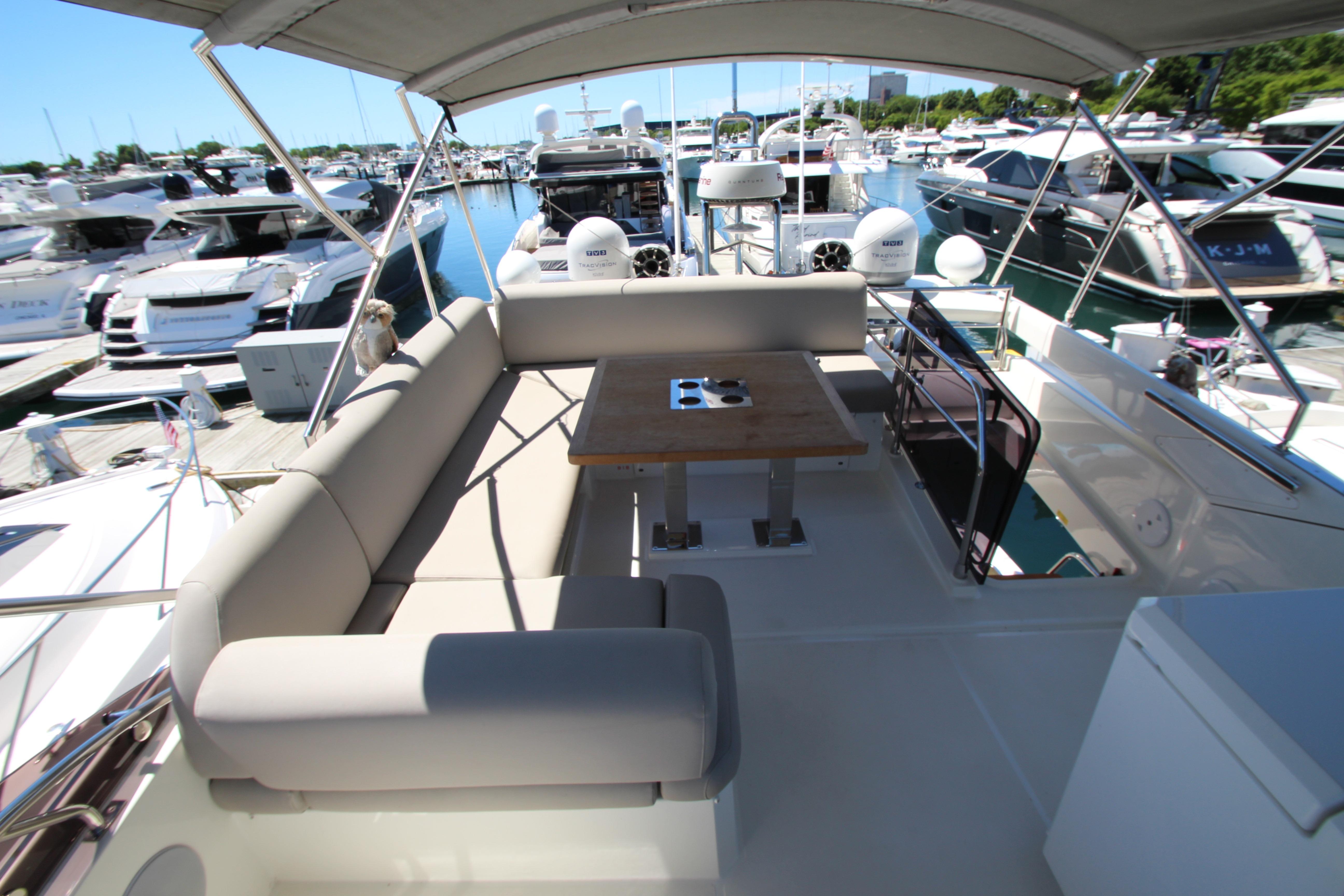 Prestige 520 yacht 2022 model, featuring a spacious deck with seating and table at marina.
